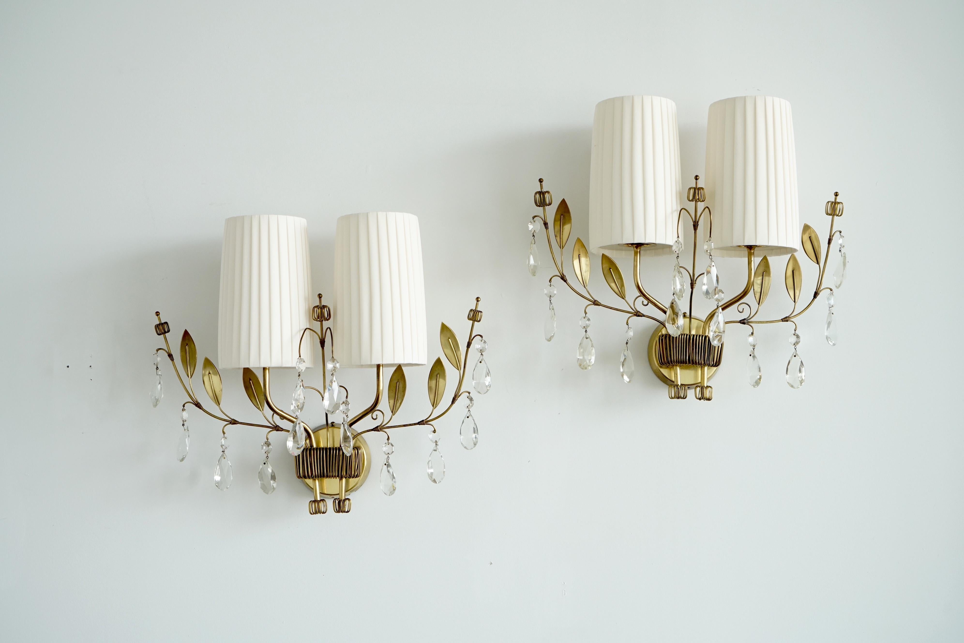 Paire de grandes appliques murales conçues par Paavo Tynell pour Taito OY, modèle 9473, Finlande, vers 1950.
Décor en laiton avec pendentifs en cristal et abat-jour en soie plissée. L 23″ ; H 19″ ; Profondeur 8″.
Câbles existants, recâblage possible
