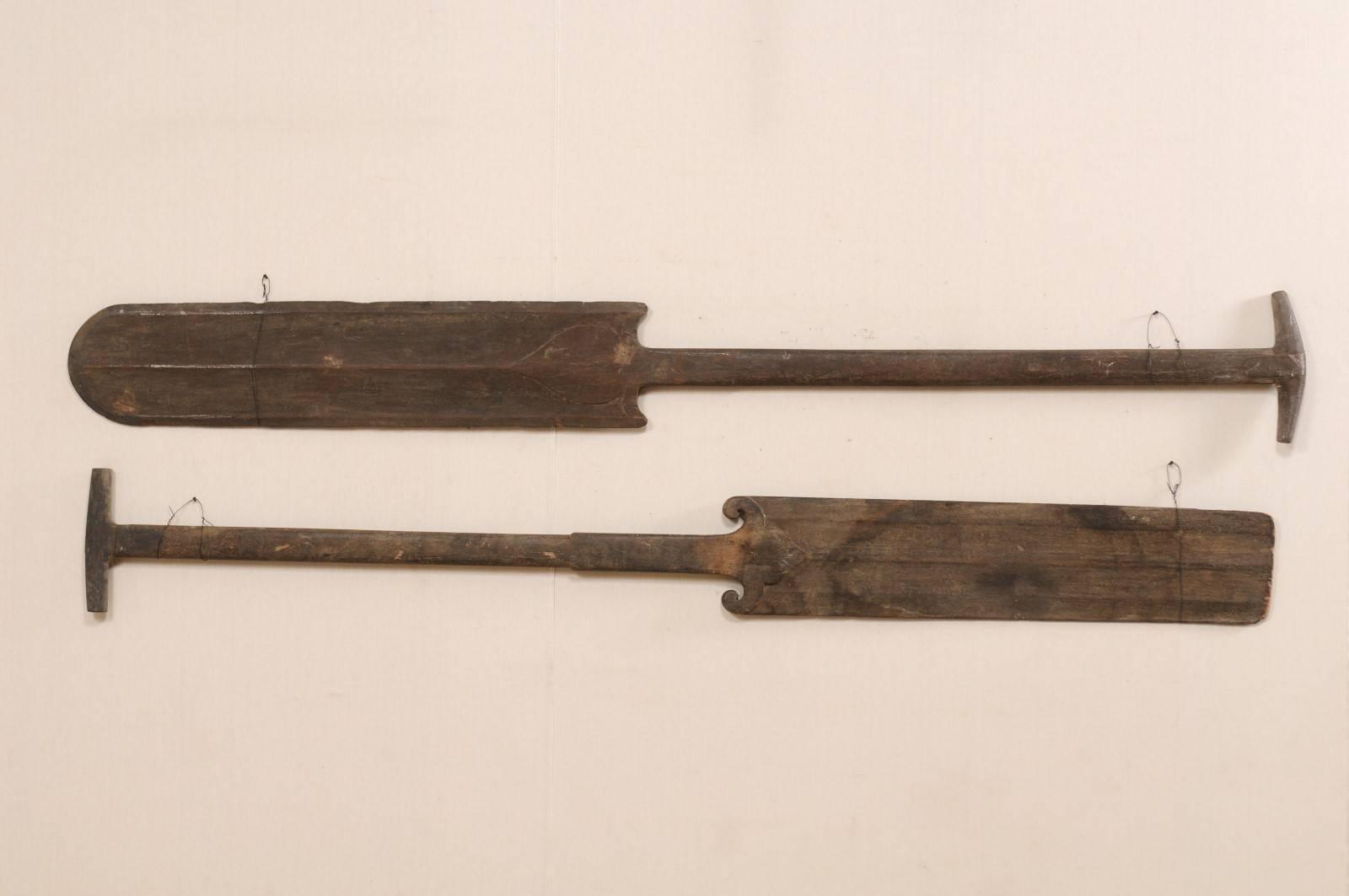 A pair of large-sized South Indian (Kerala) wooden boat steering paddles from the mid-20th century. This pair of hand-carved boat oars from Kerala is adorn with decoratively carved accents at the top of the blade with raised textured striping down