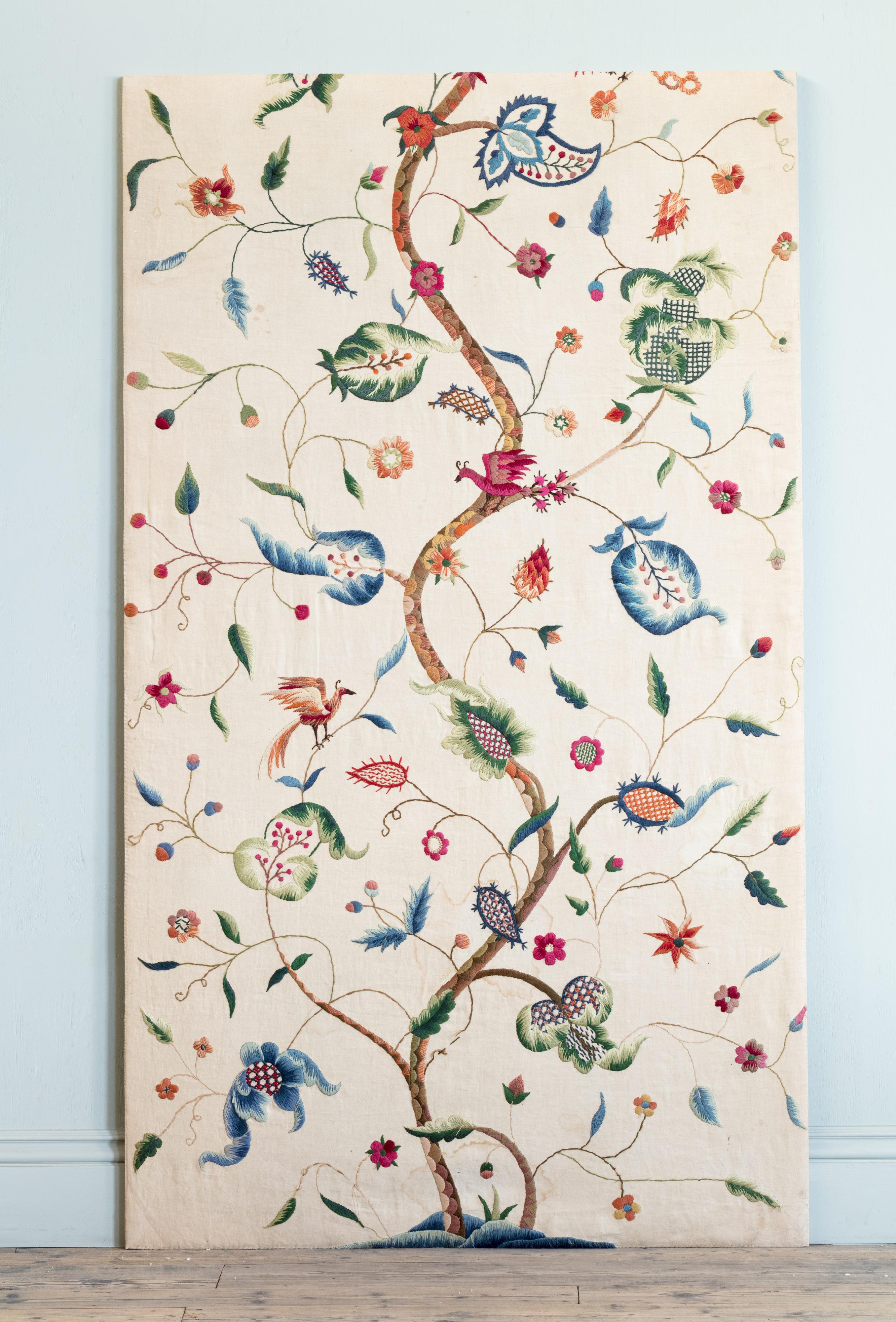 On linen ground, with central undulating stalk with perched birds and blossoming berry laden branches, embroidered in rich and colourful ‘worsted’ wool yarns. Of portrait, rectangular form.