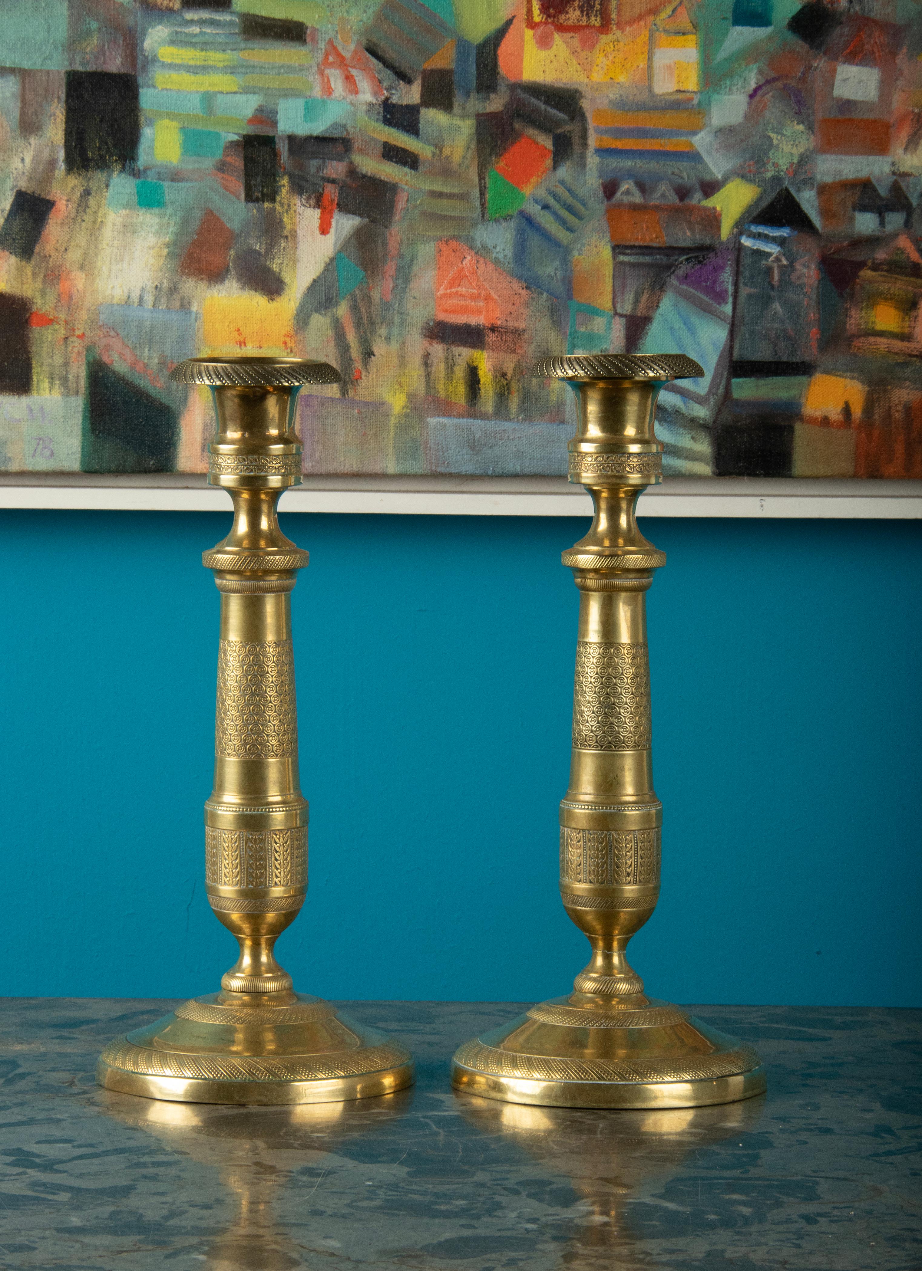 A pair of brass candlesticks. Beautifully decorated with refined silicery in Louis XVI style. The candlesticks date from around 1880-1890, originating from France. Small dents in feet, not perfectly round. 