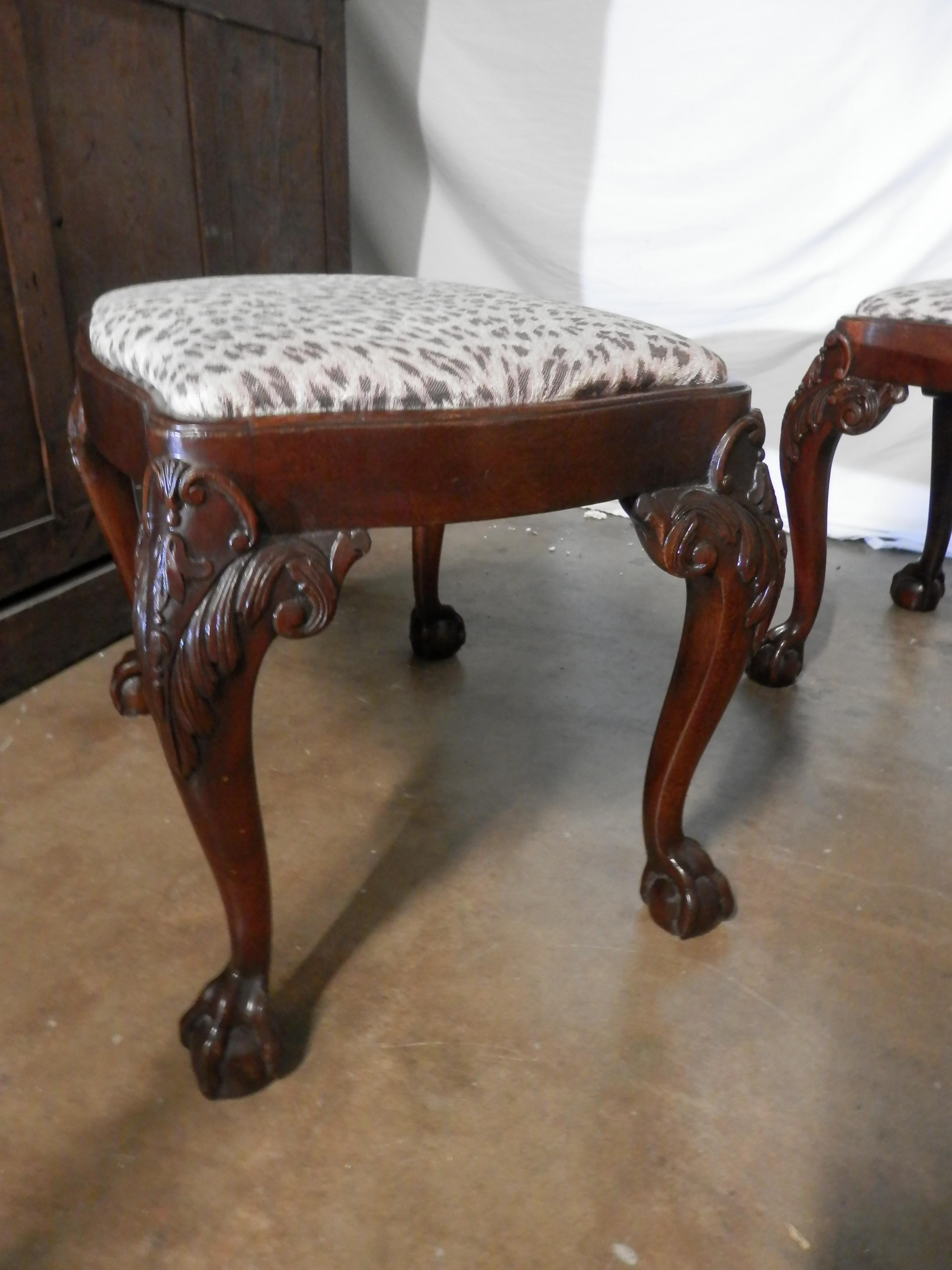 A pair of late 19th century English Chippendale mahogany stools covered in an animal print. Nicely carved acanthus knees ending in ball and claw feet