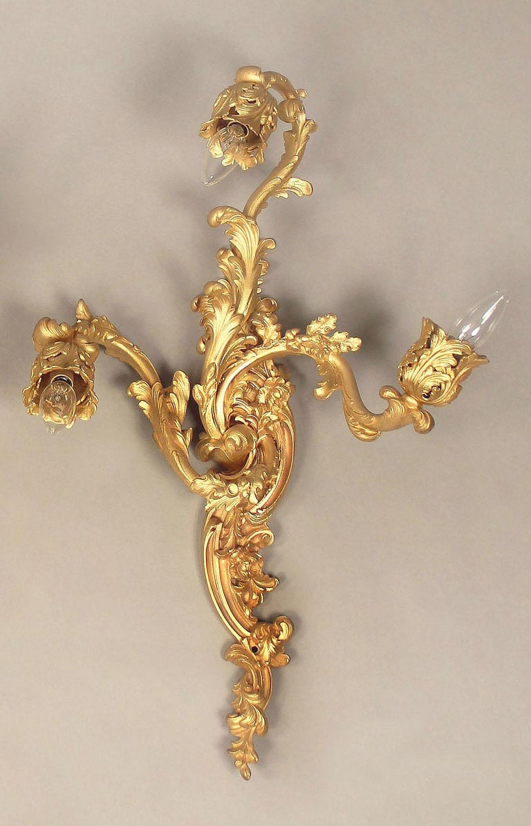 A pair of late 19th century gilt bronze three-light sconces

The backplate and arms decorated with flowers and foliage.