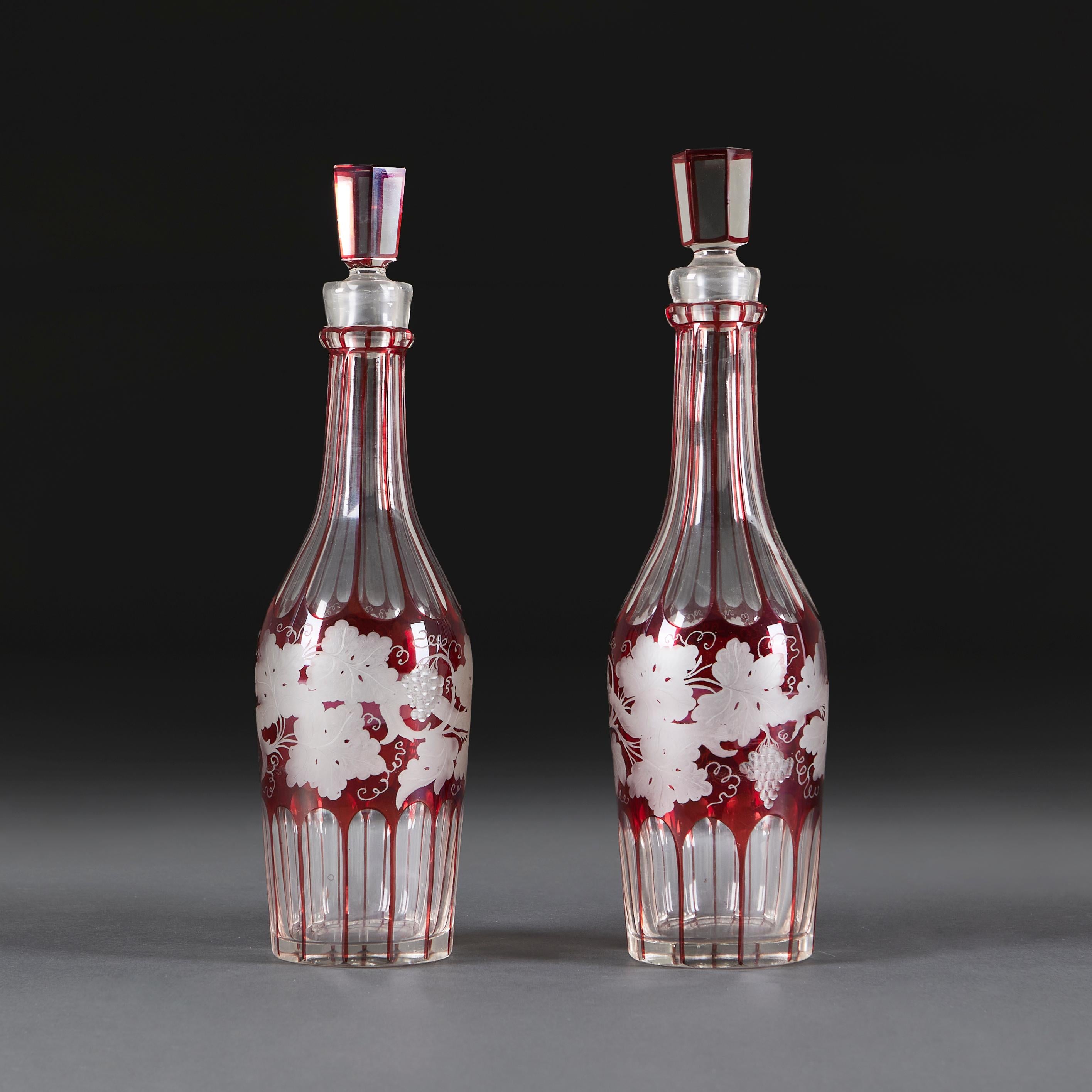 Une belle paire de carafes à alcool rouge de la fin du XIXe siècle, de forme facettée, gravées d'un décor de vigne. Ils ont conservé leur bouchon d'origine.