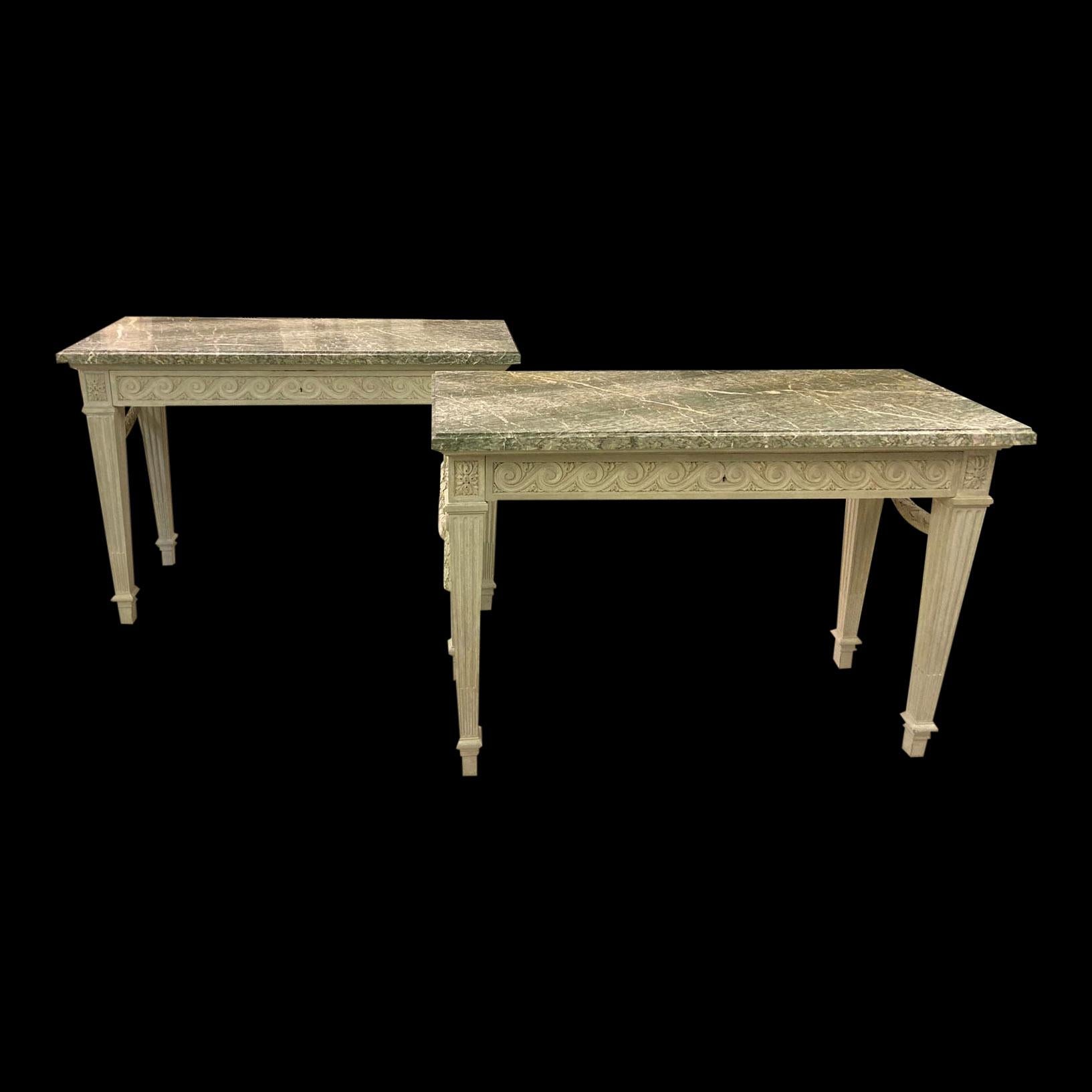 A pair of late 19th century painted wooden console tables with Cipillino Marble tops. The skirts have Vitruvian scroll decoration with Paterae corner blocks, whilst each end has a ribbon tied laurel-leaf swag draped through rings. The tapering