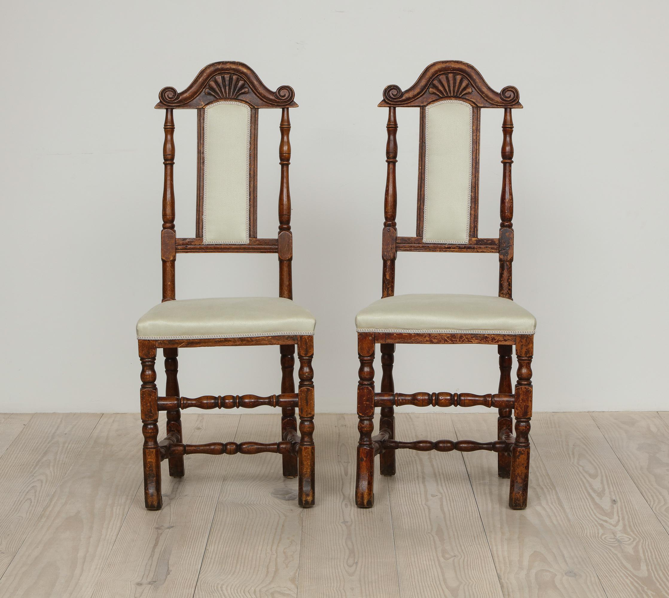 A pair of late Baroque Swedish chairs, origin: Sweden, circa 1750 -1760, reupholstered in linen sateen fabric from Rogers & Goffigon, the wood stained to resemble walnut. 

The form of these chairs, including their narrow back splat surmounted by