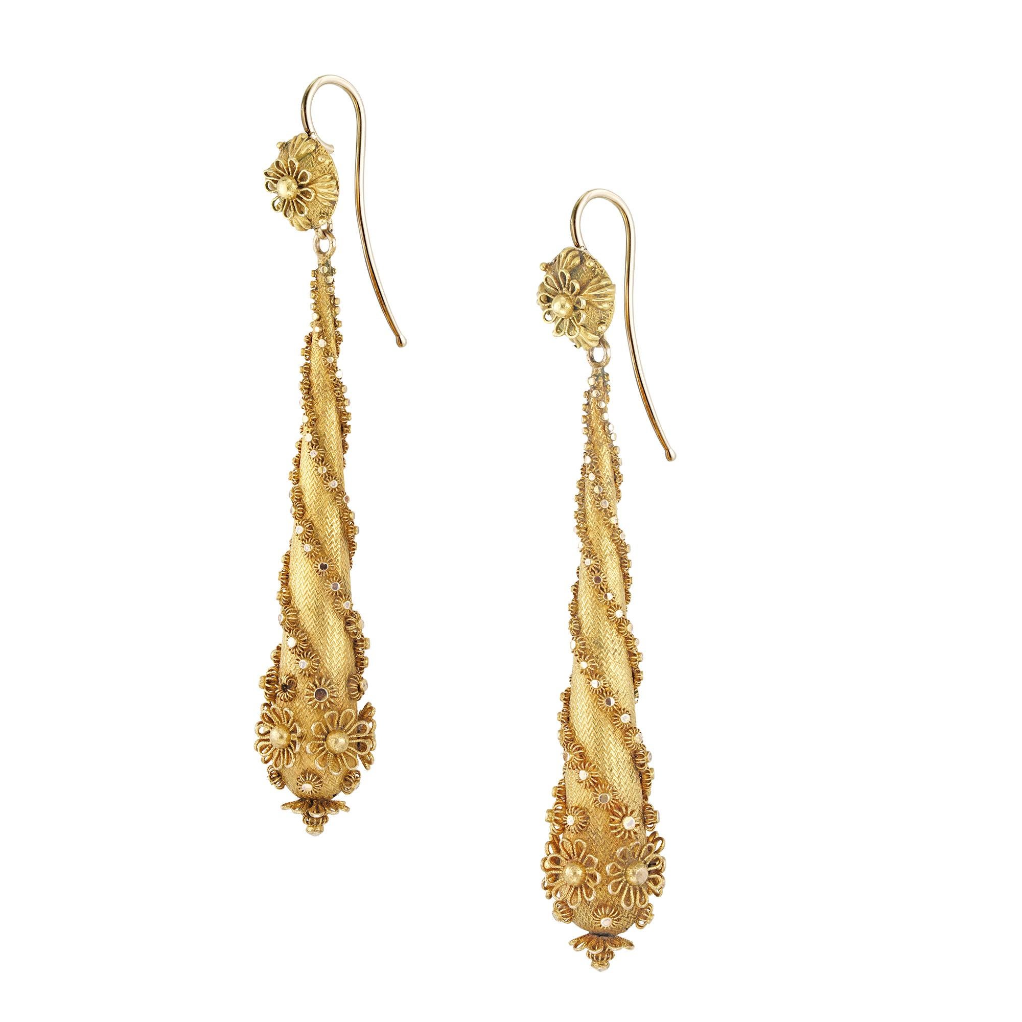 A pair of late Georgian gold drop earrings, the button-shaped top bearing a stylised filigree flower, suspending a drop with engine-turn engraved background applied with filigree flowers in a spiral design, all in 18 carat gold with hook fittings,