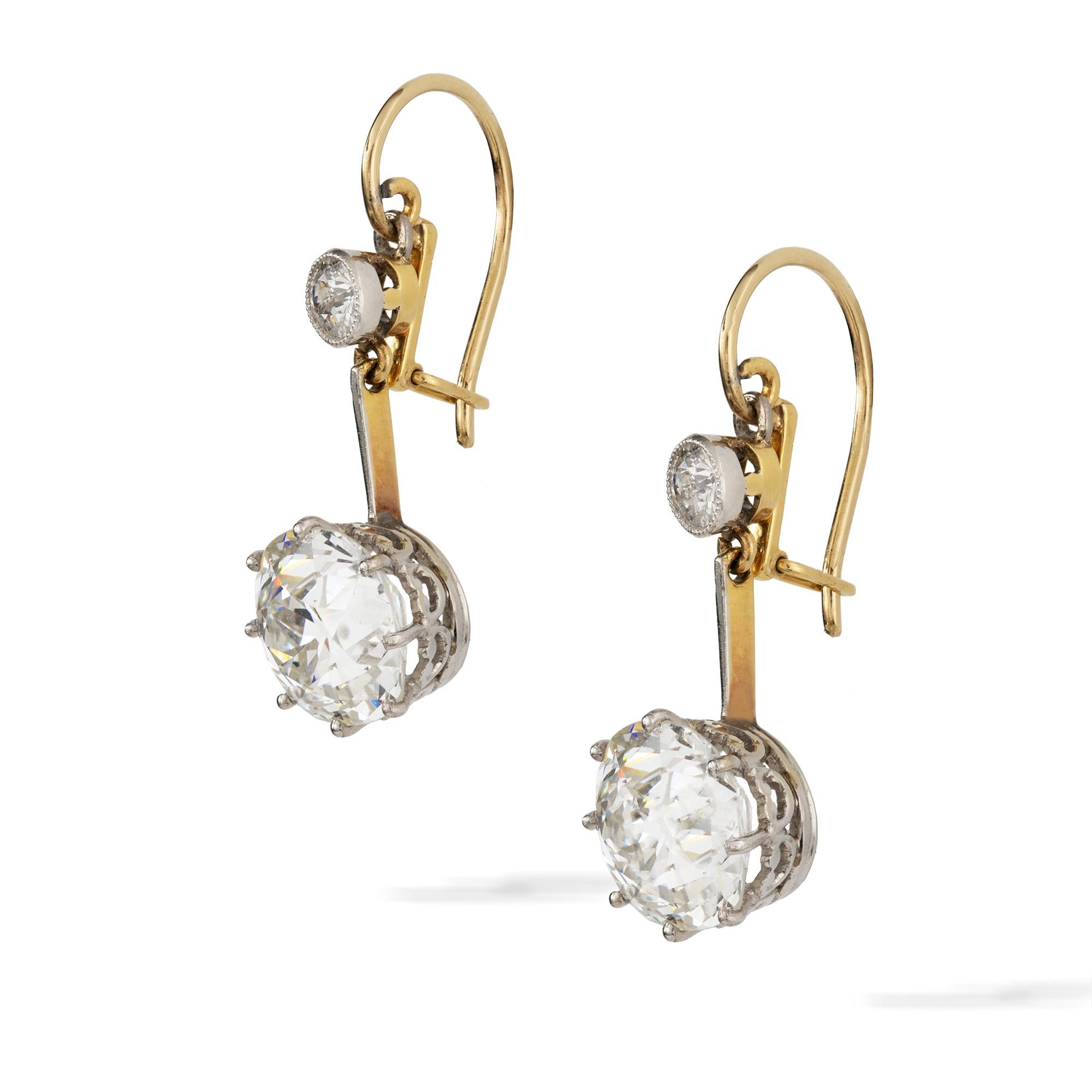 A pair of late Victorian diamond drop earrings, the old-cut diamonds, weighing 3.14 and 3.23 carats, respectively H colour VS1 and H colour SI1, accompanied by De Beers Report , each eight claw-set to a platinum scroll collet, suspended from a
