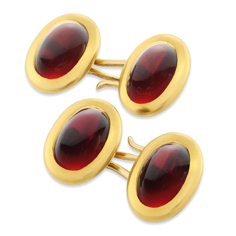 A pair of late Victorian garnet cufflinks, each cufflink comprising two plaques, each set with an oval cabochon-cut garnet, estimated to weigh a total of 17 carats, set to a yellow gold mount and surround, circa 1900, each link measuring