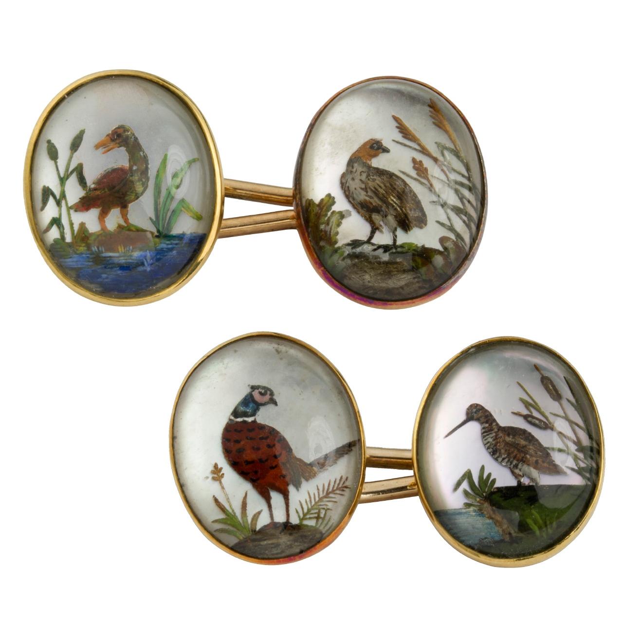  pair of late Victorian reverse intaglio crystal cufflinks, the cabochon-cut crystal faces each depicting different images of game birds, each set on an 18 carat gold rubover mount, connected by a baton fastening, hallmarked 18 carat gold, circa