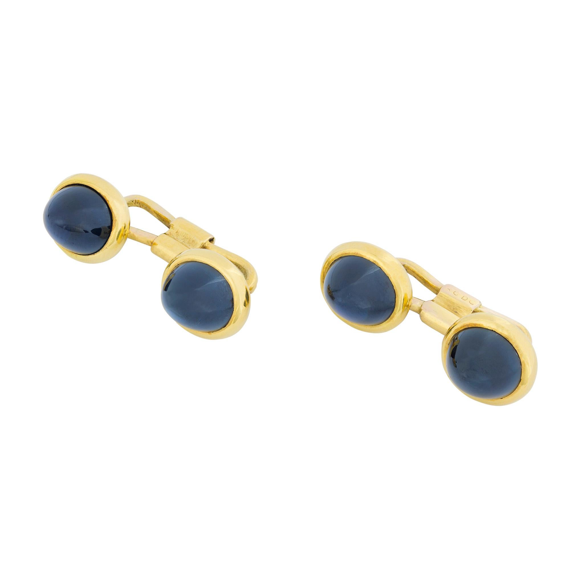 A pair of late Victorian sapphire and yellow gold cufflinks, each cufflink comprising two plaques, each set with a circular cabochon-cut sapphire, the four sapphires measuring approximately 8.4 x 7.4 mm, all set to yellow gold mounts with