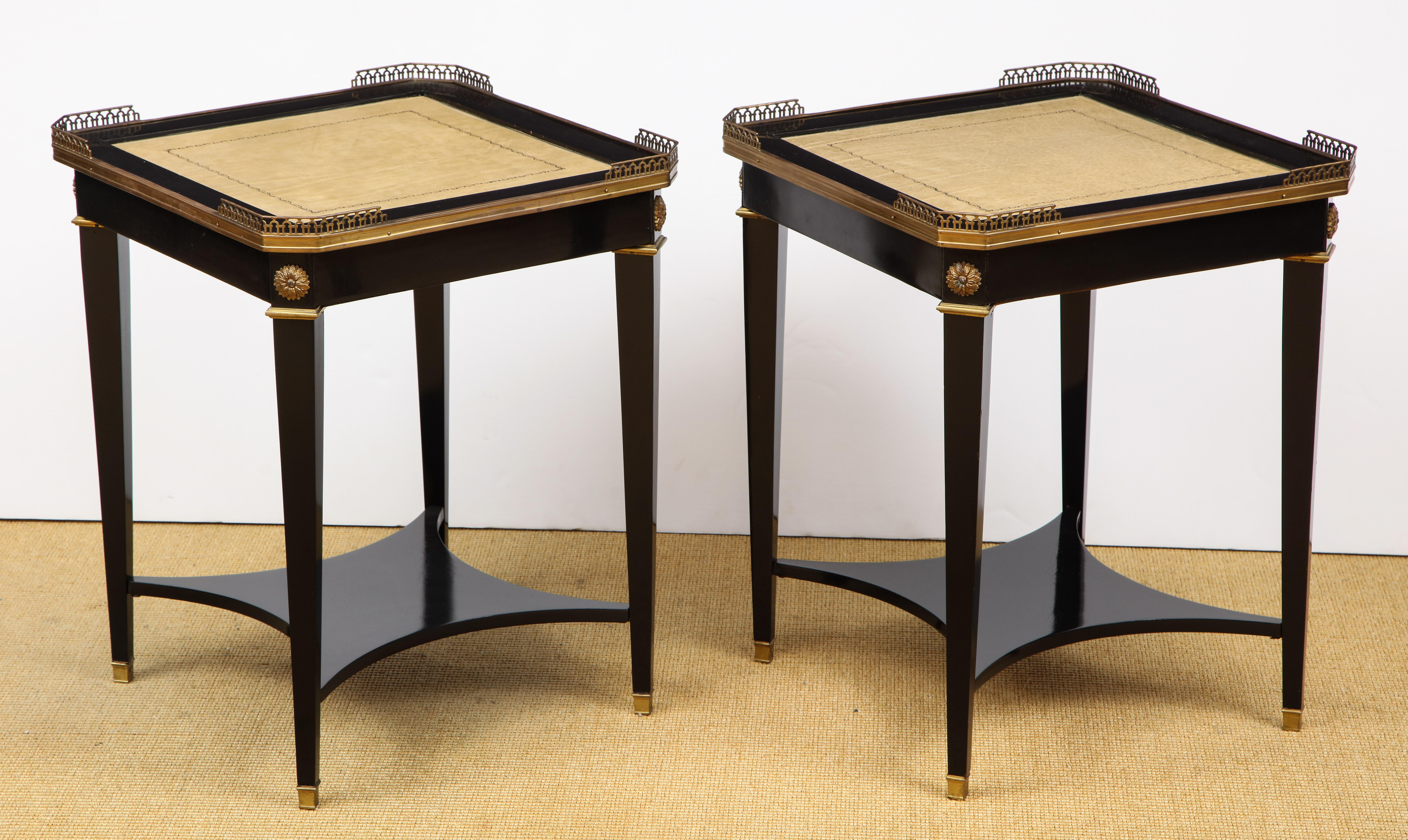 The Louis XVI style tables, each with a hammered leather top and brass gallery supported by four brass mounted tapering legs having a central shelf, stamped JANSEN.