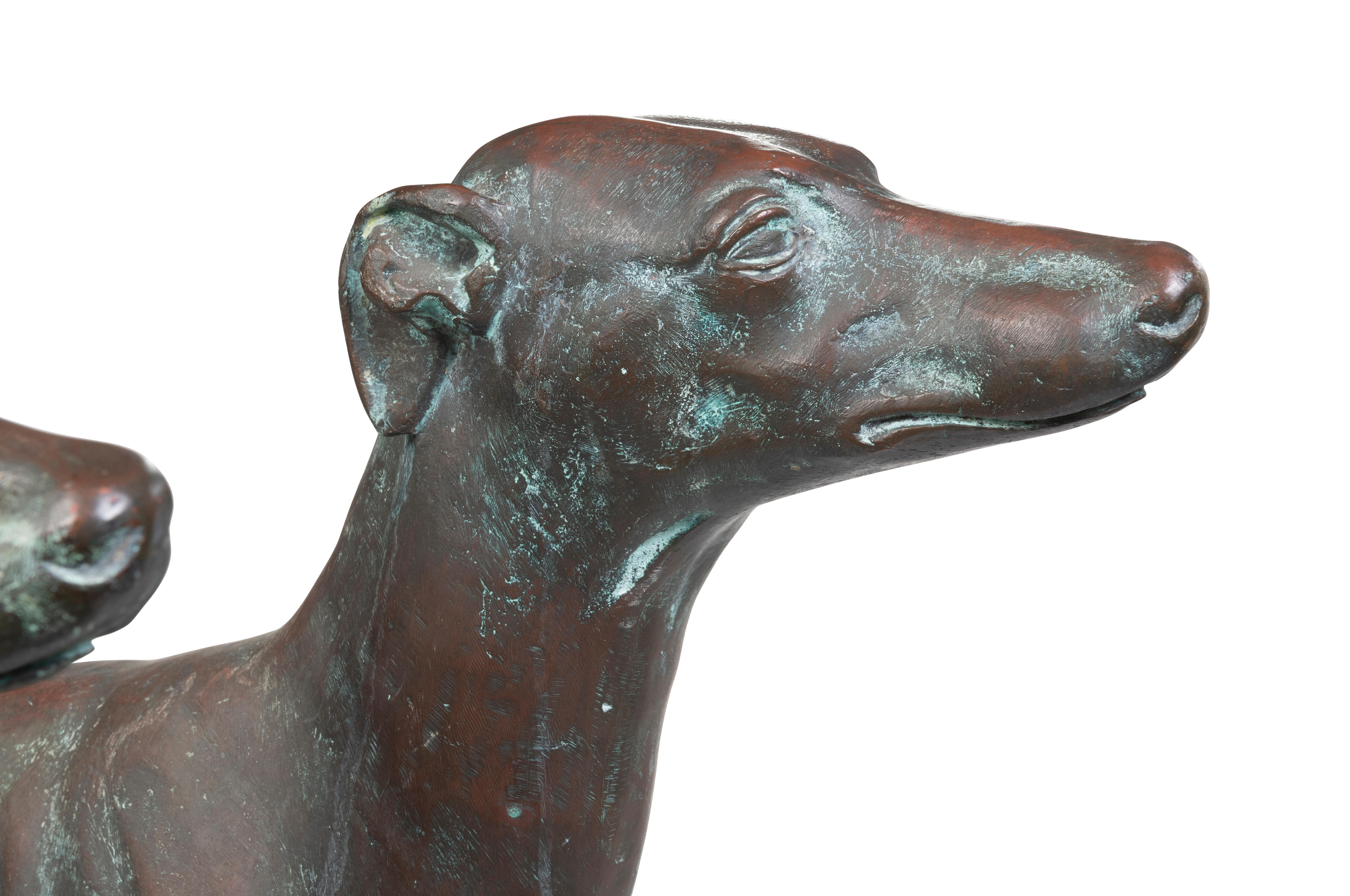 A Pair of Life Size Bronze Sighthounds

Description:
A handsome pair of life-size opposing sighthounds, hollow cast in bronze from late 18th – early 19th century English lead originals. Both are finely shaped and lithe, standing with heads erect and