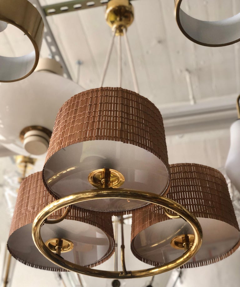 A pair of Chandeliers designed by Paavo Tynell for Hotel Vaakuna in Helsinki, Finland, circa 1940.
Frosted glass diffusers with wood stripes shades and 3 Edison type bulb sockets.
Dimensions: Diameter 25
