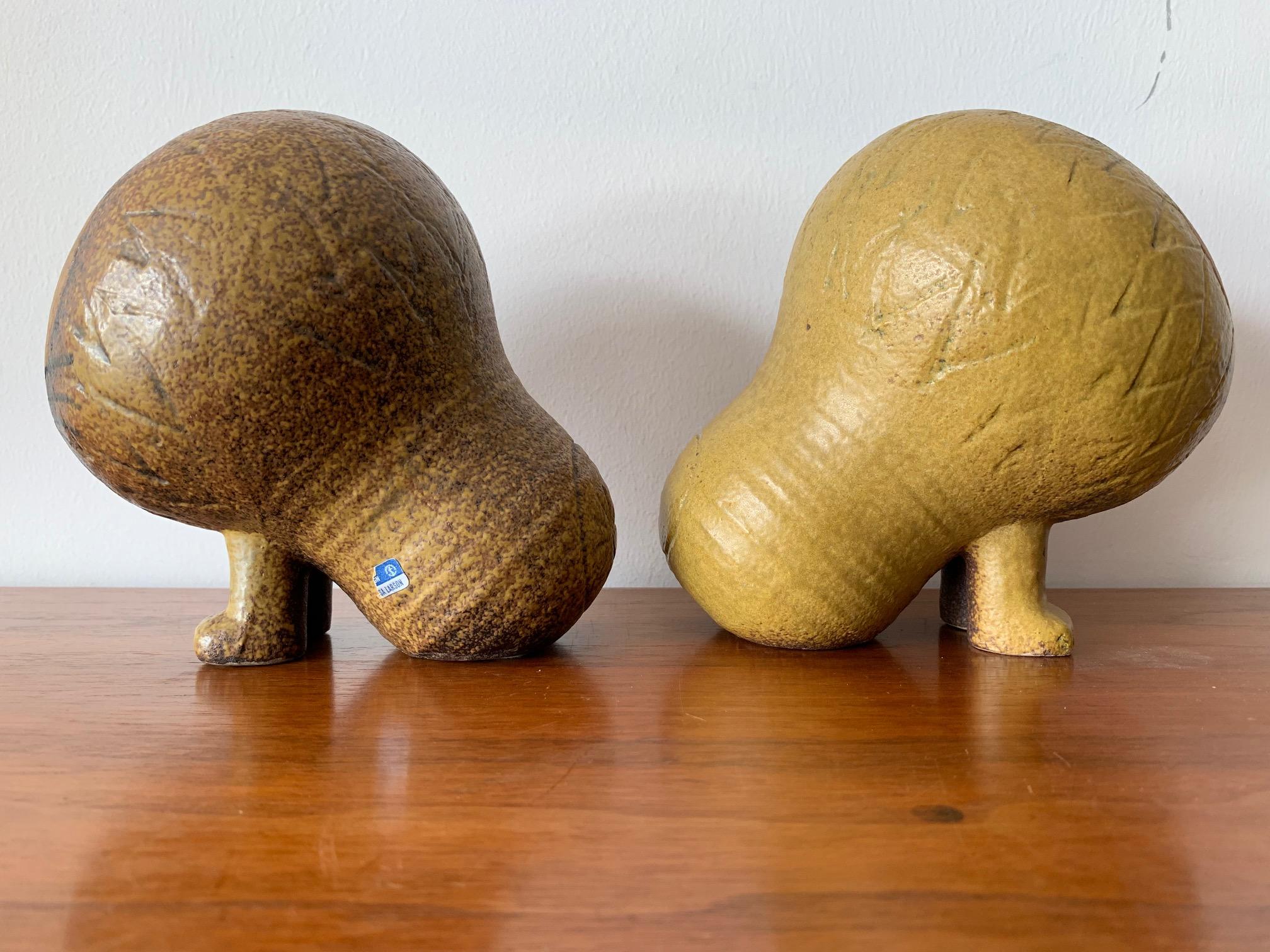 A pair of large lion ceramic sculptures by Lisa Larson for the Africa Series made by Gustavsberg. This size is the largest of the series. Signed at bottom. Whimsical interpretation and beautifully crafted. One has a slightly darker glaze and is a