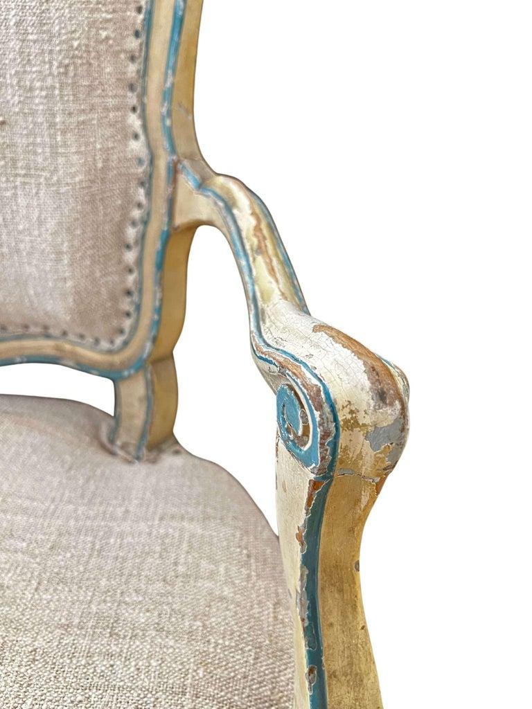 A Pair of Louis XV style fauteuils (arm chairs), featuring the curved lines characteristic of the Louis XV style. The frame is painted in a chalky white, accented with a beautiful peacock blue color. Raised on cabriole legs, the chairs are