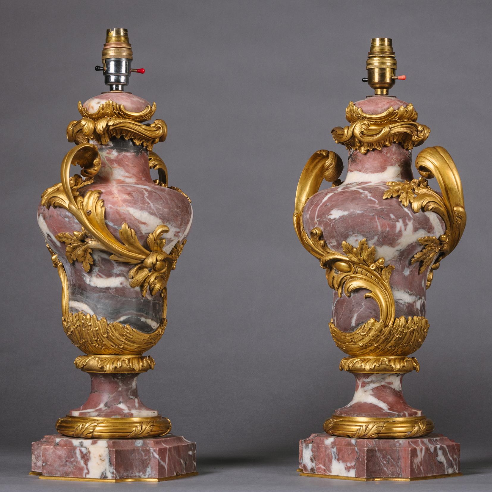 Ein Paar Vasen aus vergoldetem, bronzenem und rosa Marmor im Louis XV-Stil, die als Lampen dienen.

Jede Vase aus Fleur de Pêcher-Marmor, umrankt von einer reichen Rocaille aus vergoldeter Bronze und Griffen mit Akanthusranken.

Frankreich, ca. 1890.