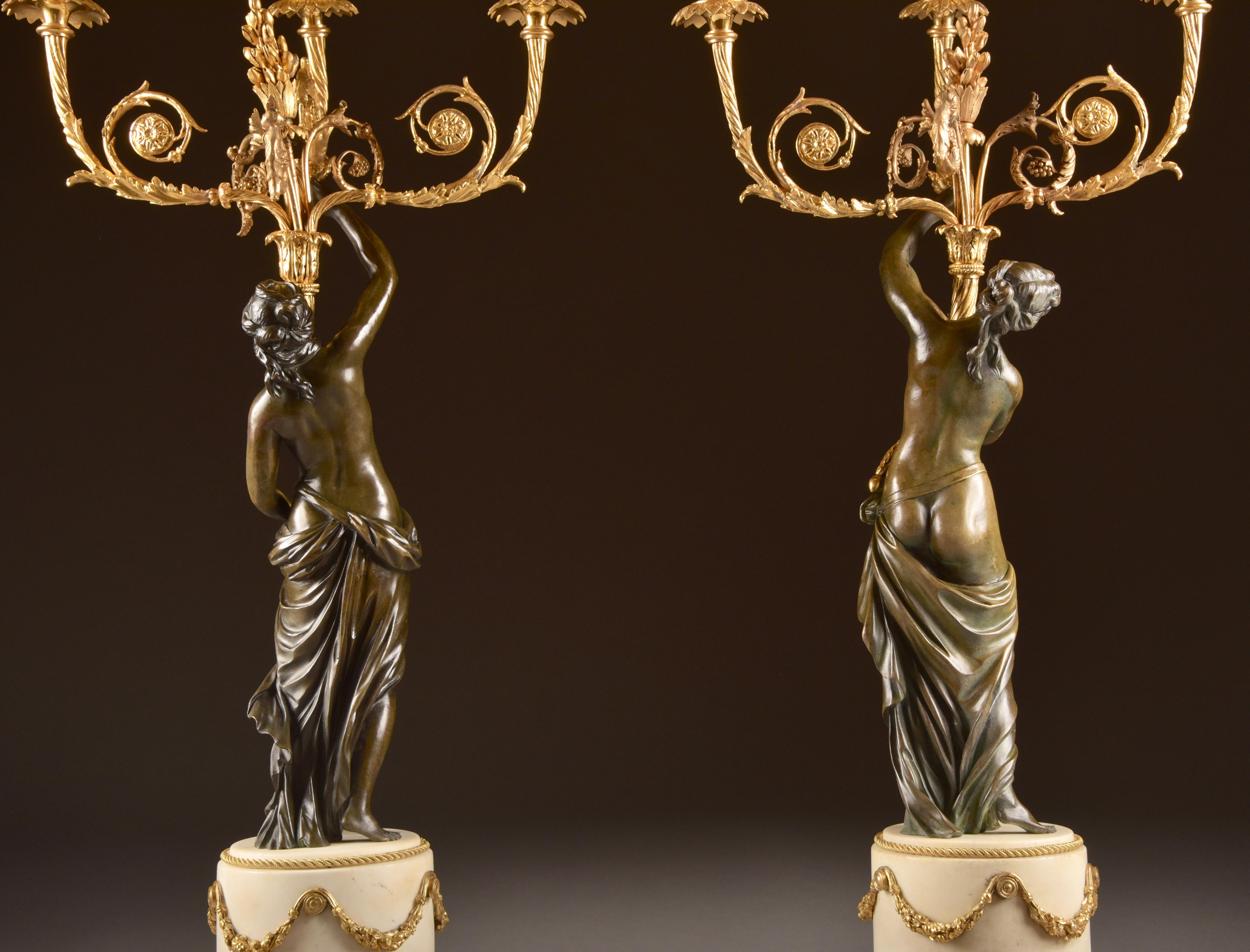 A big (62 cm) pair of very beautiful patinated bronze of female nude, three-armed French candlesticks, on white marble base.