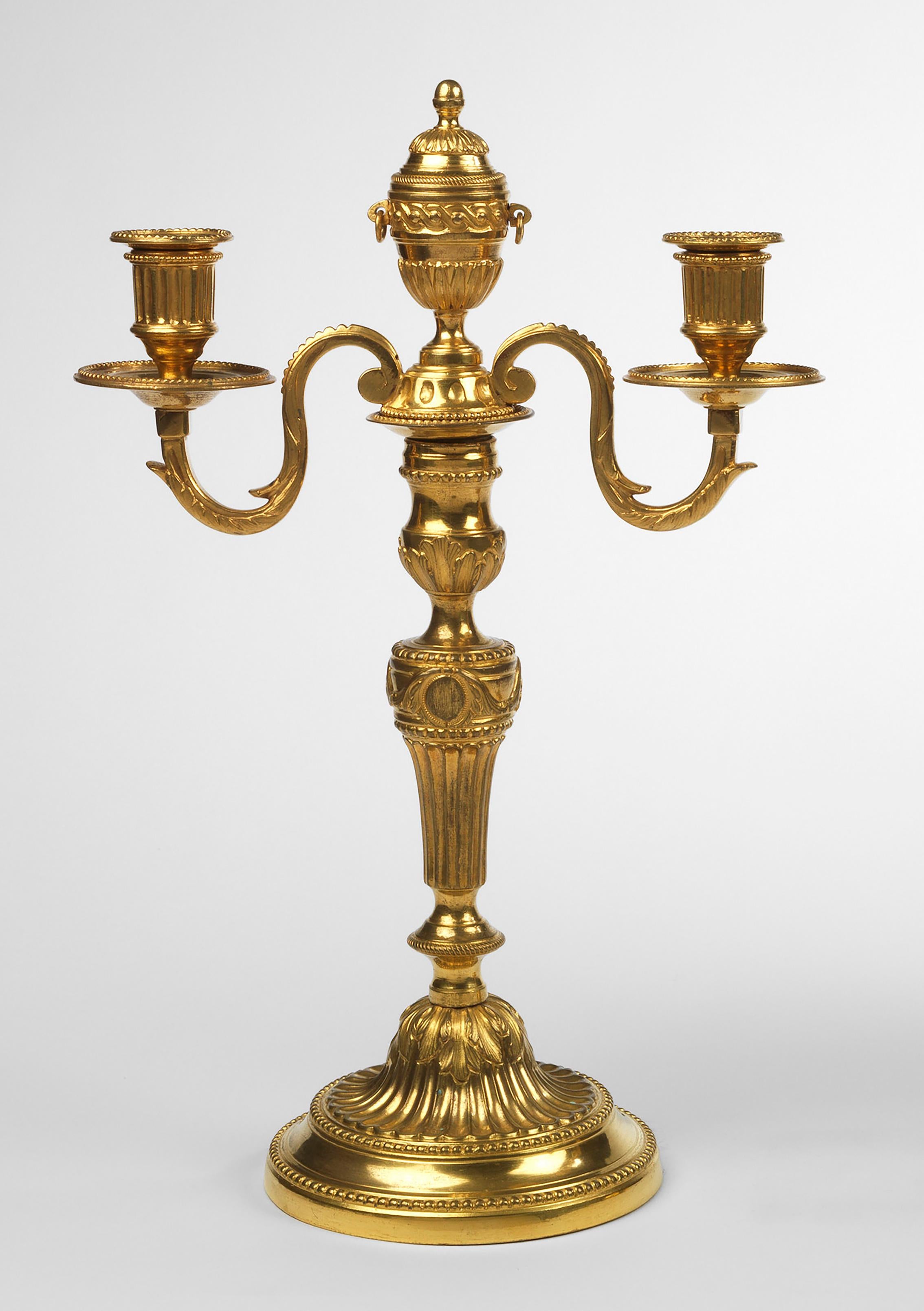 The acanthus asymmetric scrolling arms, with reeded nozzles and detachable beaded drip pans above beeded, circular collars; surmounted by a central carved and decorated pedestal urn with cone finial and circular handles; the fluted and acanthus