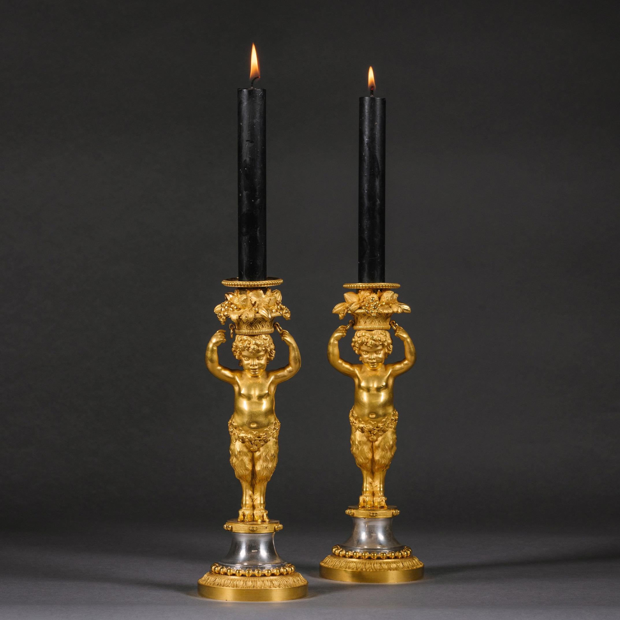 A Pair of Louis XVI style gilt-bronze and polished steel candlesticks
By Emmanuel-Alfred (dit Alfred II) Beurdeley.

Stamped 'BY' for Beurdeley. 

Each modelled as a bacchic putto standing on a tambourine holding atop his head a basket of fruit