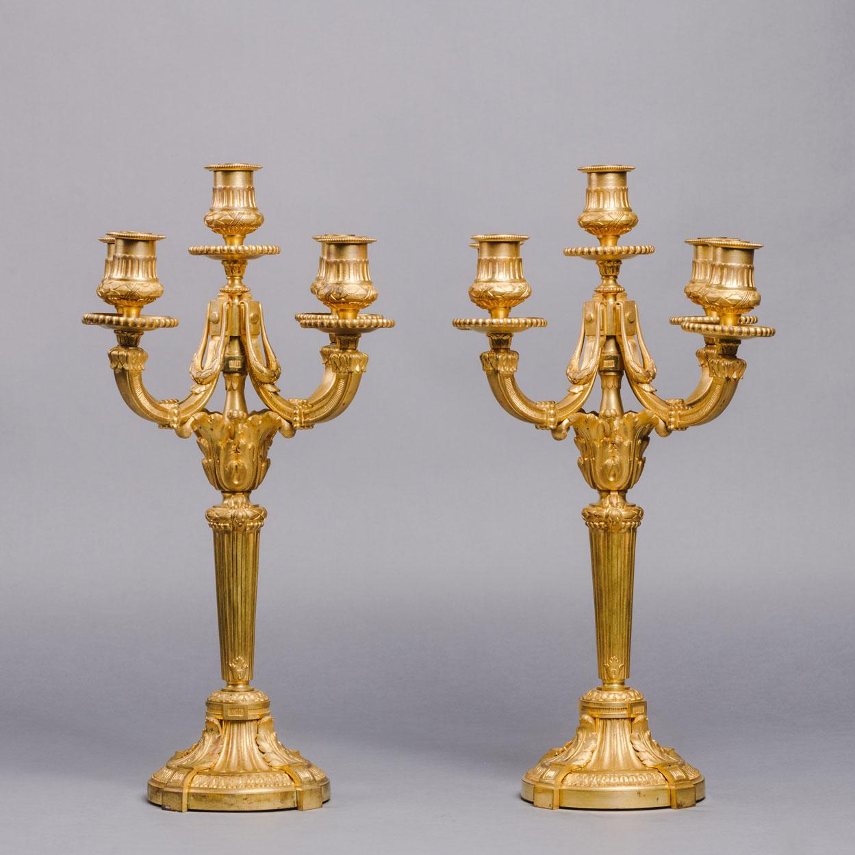 A Pair Of Louis XVI Style Gilt-Bronze Five-Light Candelabra Or Table Lamps
By Jollet Et Cie, Paris

Each with fluted stem supporting central light and issuing four swept branches. Presently not wired for electricity, they can be wired upon