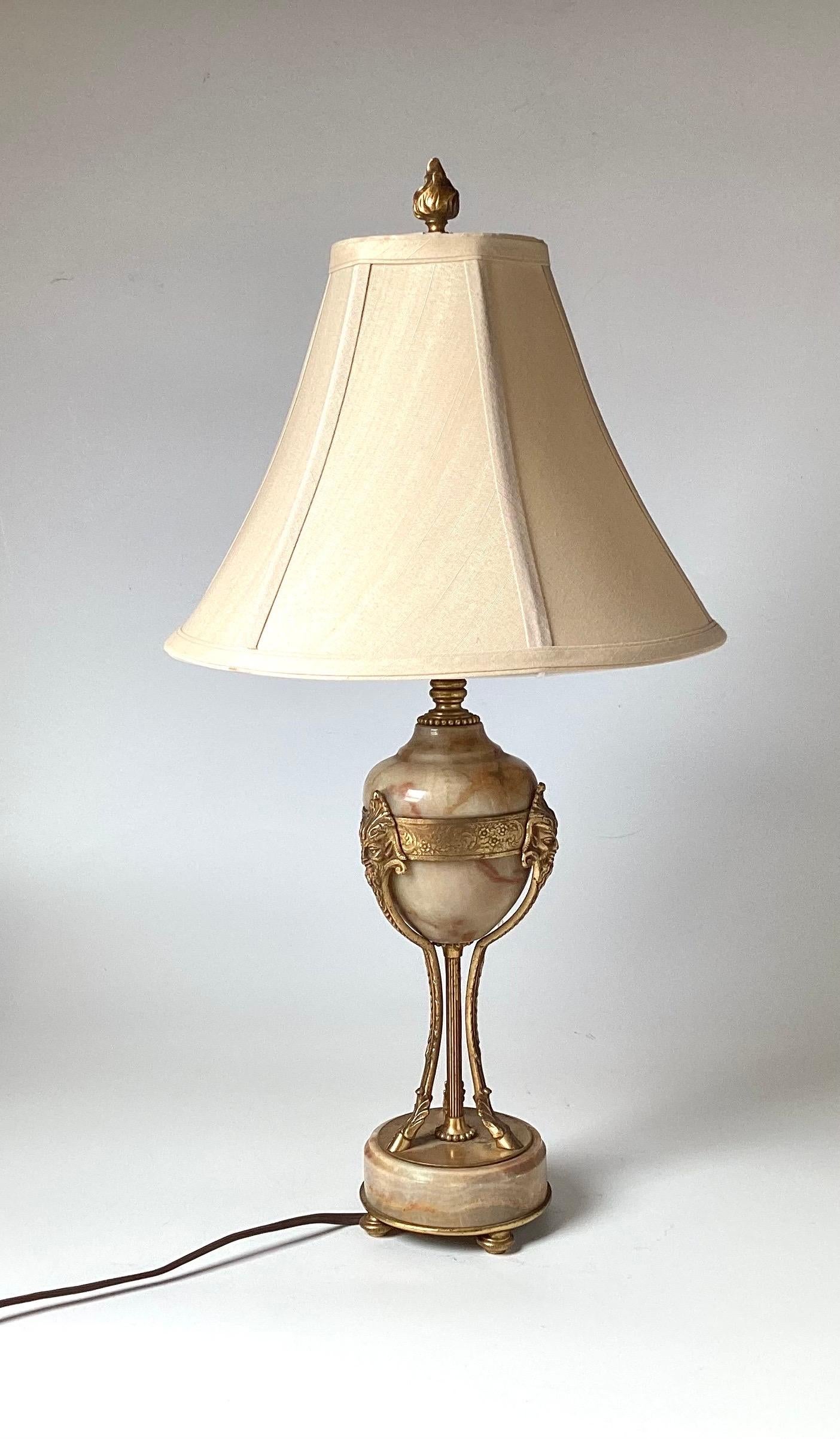 An elegant pair of Louis VXI style Bronze and marble diminutive table lamps with oval marble body with three gilt bronze legs attached to a round base.  The lamps are 21 inches tall, 4.5 inches in Diameter.  The shades are for photographic purposes