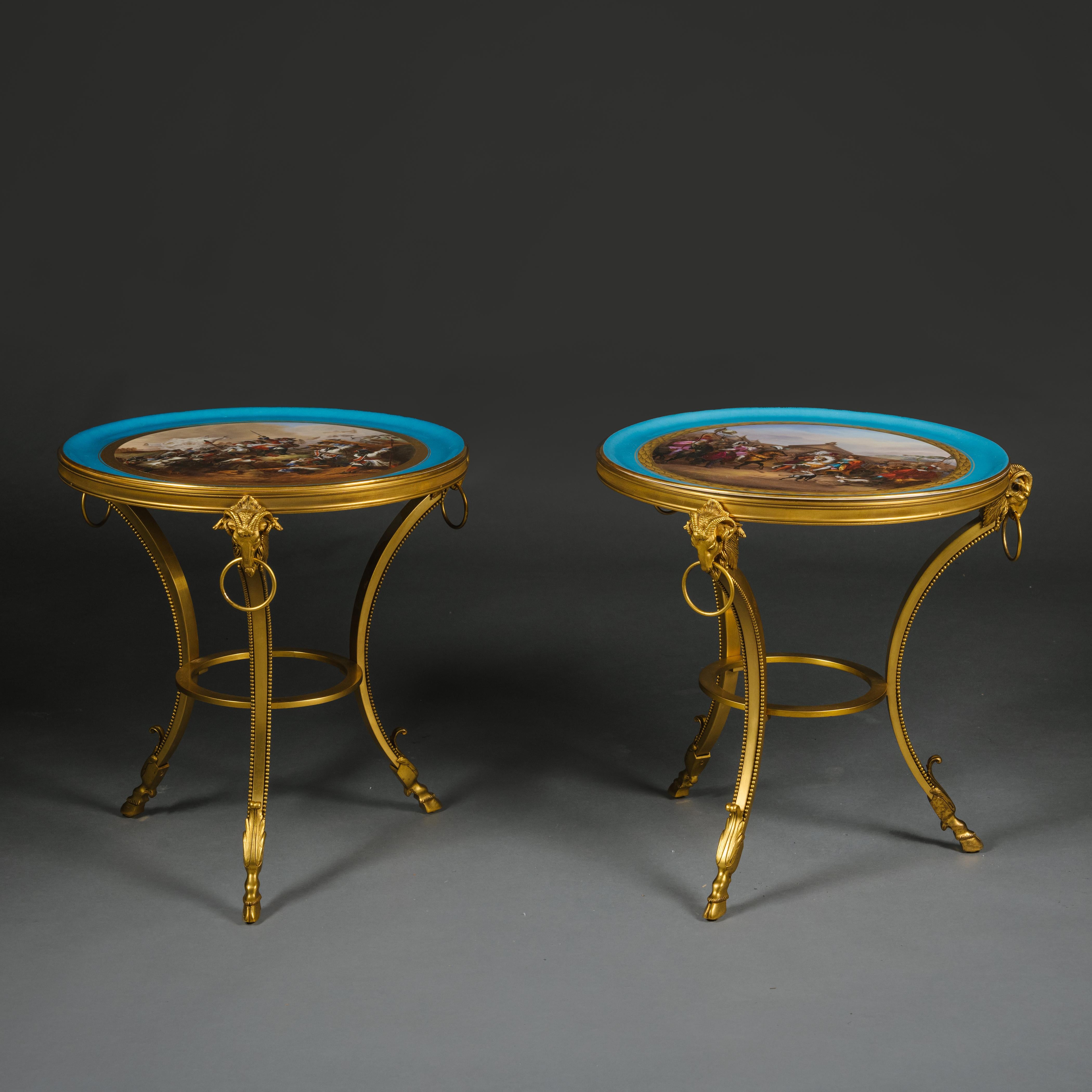 A Fine and Unusual Pair of Louis XVI Style Gilt-Bronze Low Side Tables With Sèvres-Style Porcelain Tops.

Each table has a fine Sèvres-style porcelain charger painted with historical battle scenes within bleu céleste borders supported on finely cast