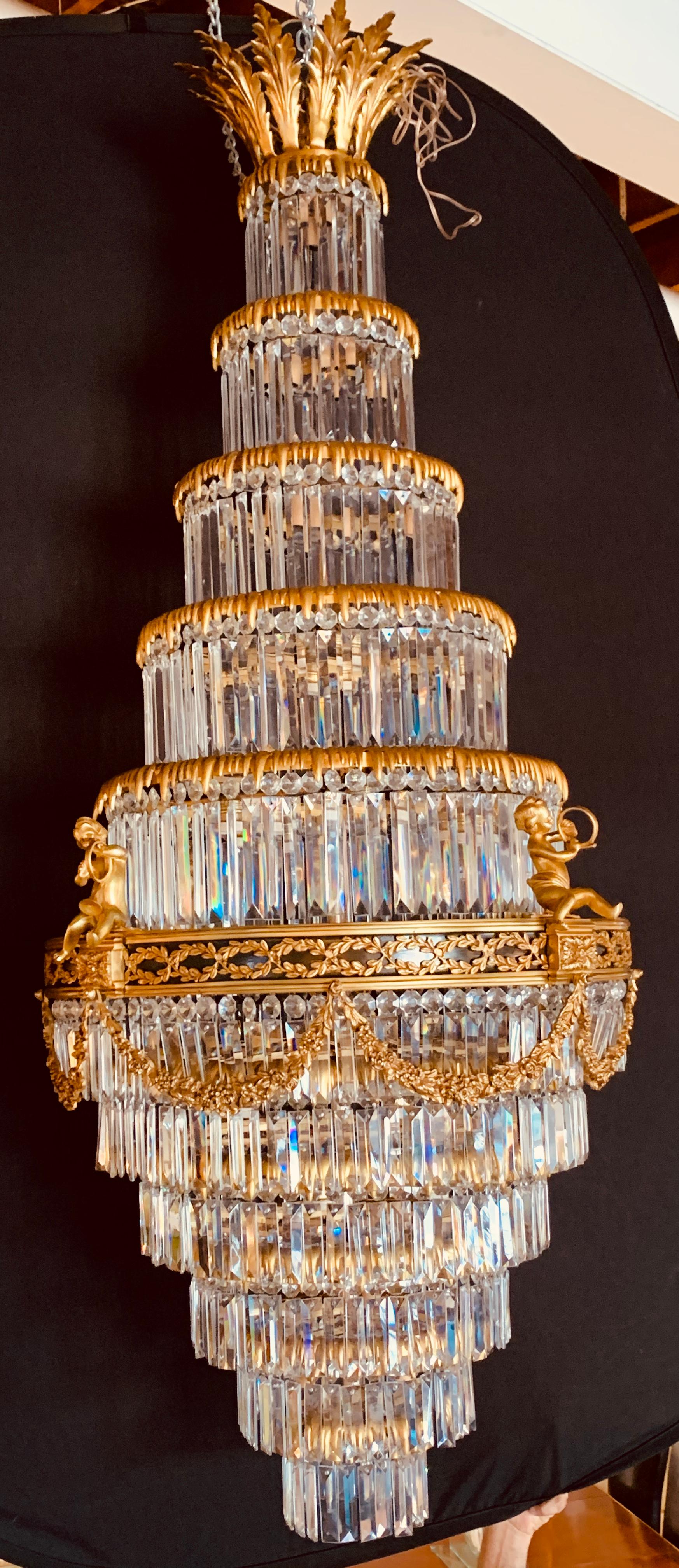 A pair of Louis XVI style gilt bronze & crystal swag form neoclassical chandeliers. stunning beyond words are these one of a kind pair of king crowned lights. each having a Fine cut crystal drapery form of tiers all layered in bronze circular