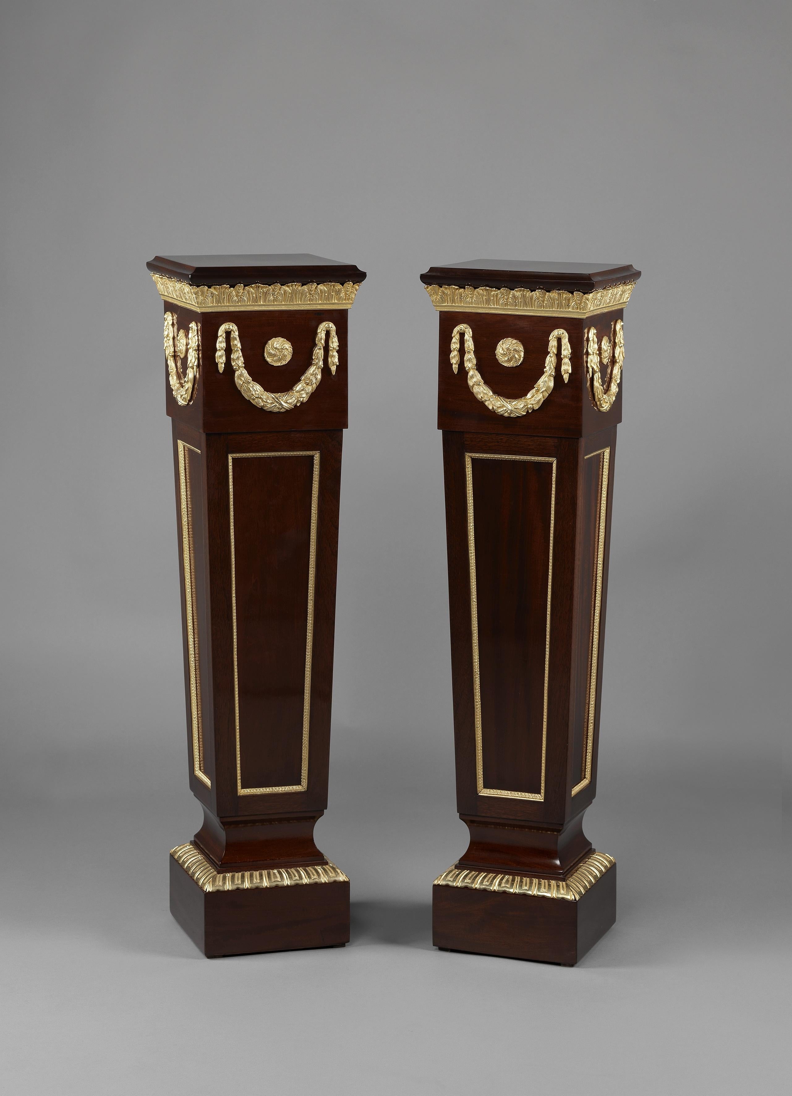 A pair of Louis XVI style gilt-bronze mounted mahogany pedestals. 

French, circa 1900. 

Each pedestal is of tapering square section with gilt bronze garlands and acanthus bands.