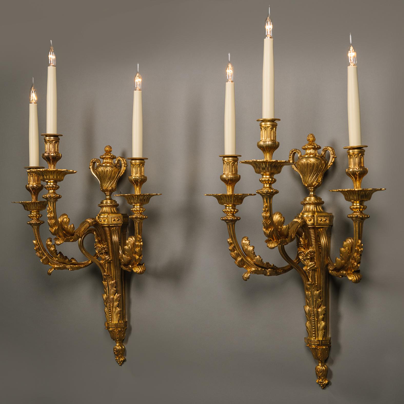 Paire d'appliques murales à trois lumières en bronze doré de style Louis XVI. 

Chacun avec une plaque arrière effilée en forme de carquois de flèche et surmontée d'une urne. Émission de trois branches enveloppées d'acanthes en forme de 