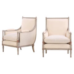A pair of Louis XVI style grey painted and partial gilt Bergere chairs, C. 1940.
