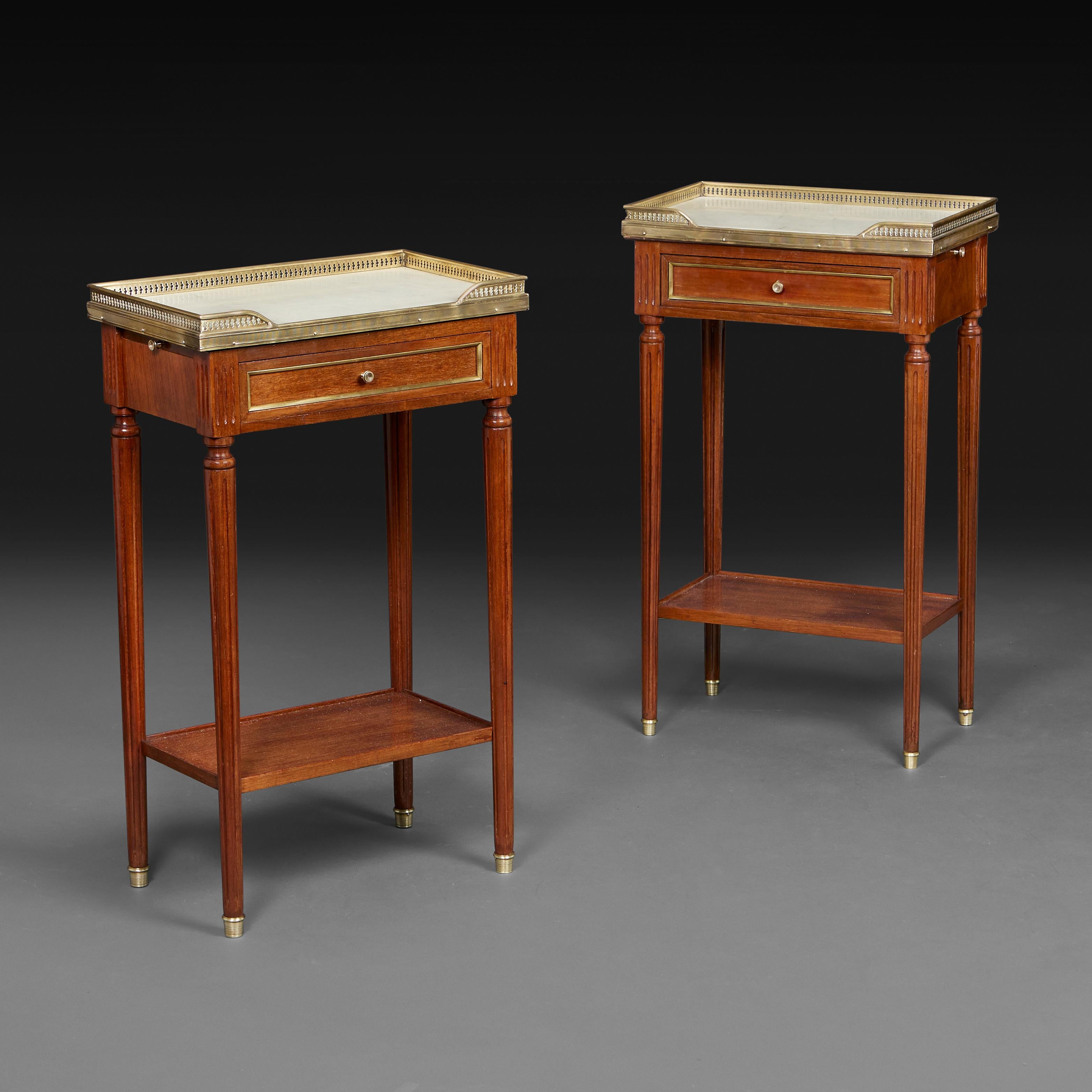 France, circa 1890

A pair of Louis XVI style mahogany bedside tables with white marble tops, brass galleries, reading slides to one side and a single drawer to the frieze, all supported on fluted and tapering legs terminating in brass