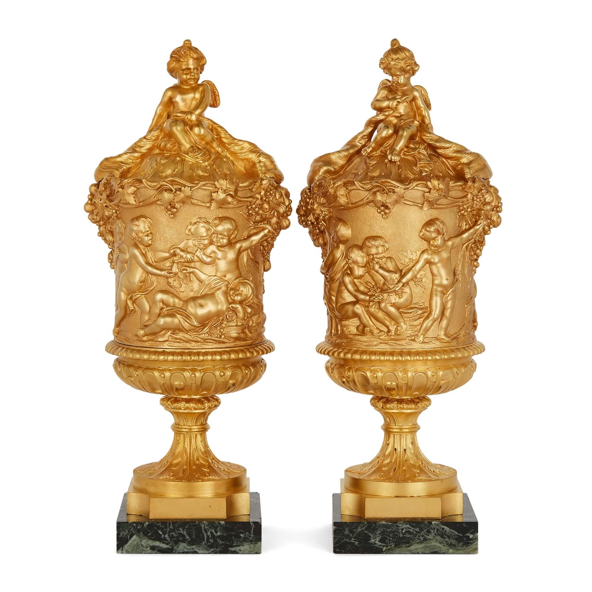 A pair of Louis XVI style ormolu lidded urns with designs in the style of Clodion
French, 19th century
Measures: Height: 44cm, width 18cm, depth 15cm. 

Crafted in the 19th century and heavily in debted to Clodion, the nineteenth century French