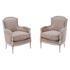 A pair of Louis XVI style painted and gilt bergere chairs, C. 1950.
