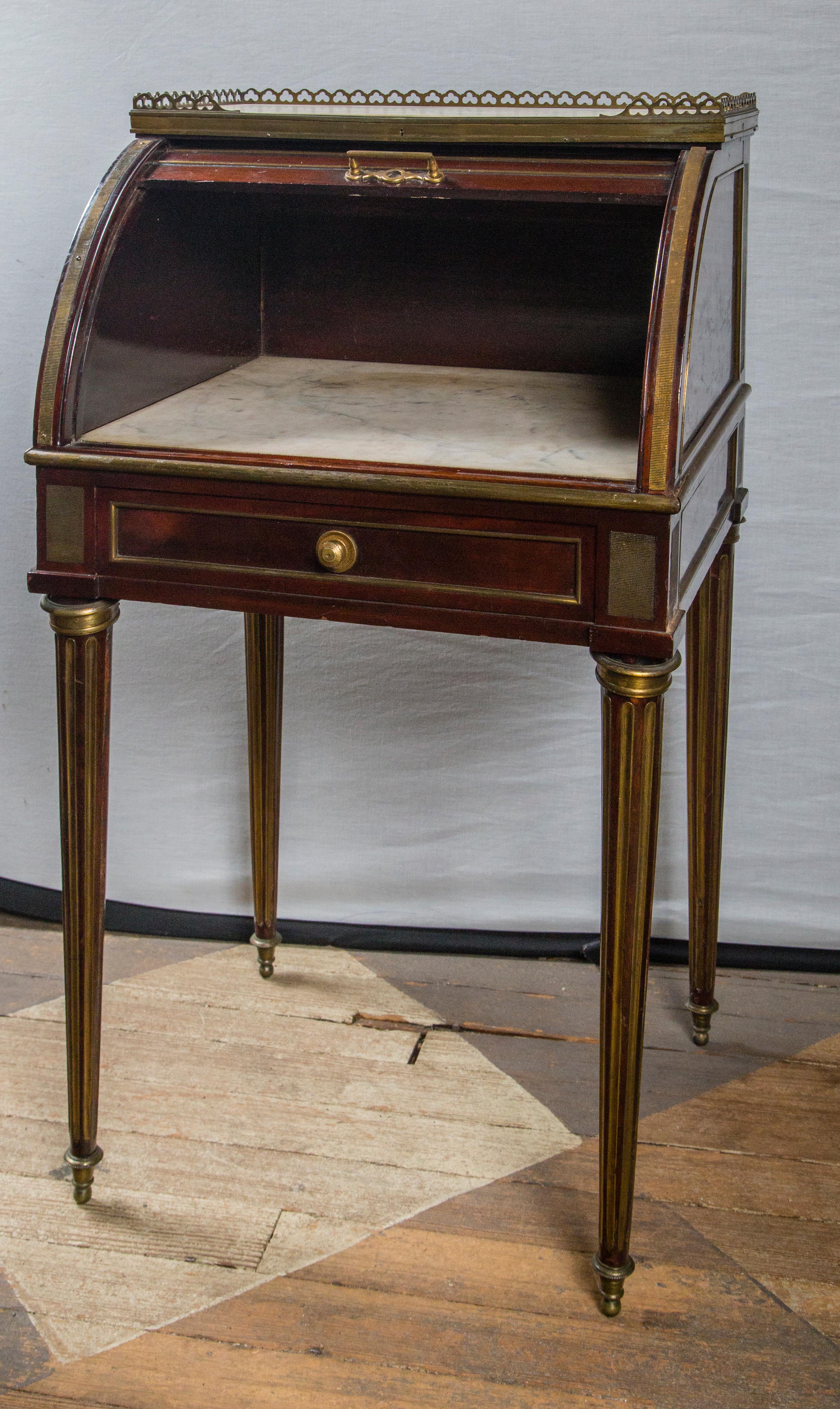 These can be sold separately. The price shown is for the pair.
Mahogany with brass mounts, even between the slats of the cylinder.
Round tapered legs with brass in the fluting. Brass toupee feet
Single drawer. Inset marble top surrounded by a