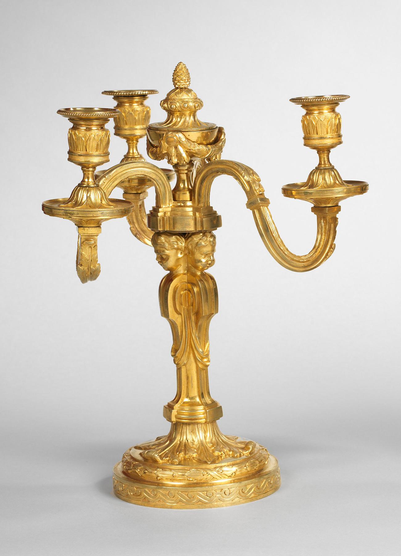 The acanthus asymmetric scrolling arms with palmette nozzles and detachable beaded drip pans above inverted lotus domed circular collars; surmounted by a central ribbon tied laurel garlanded pedestal urn with pine-cone finial; the baluster stem
