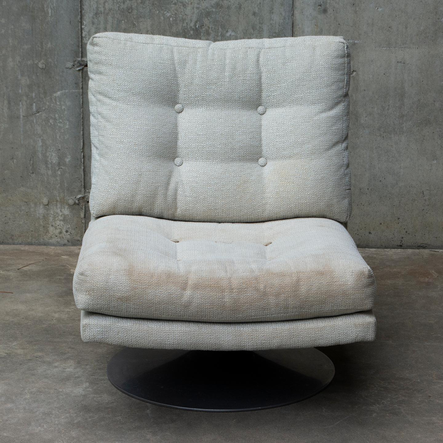 Offering a unique pair of mid-century modern swivel lounge chairs in the style of Geoffrey Harcourt. Buttoned padded seating in soft gray chenille upholstery with a black metal base. Aesthetically tasteful in both color and style. While the fabric