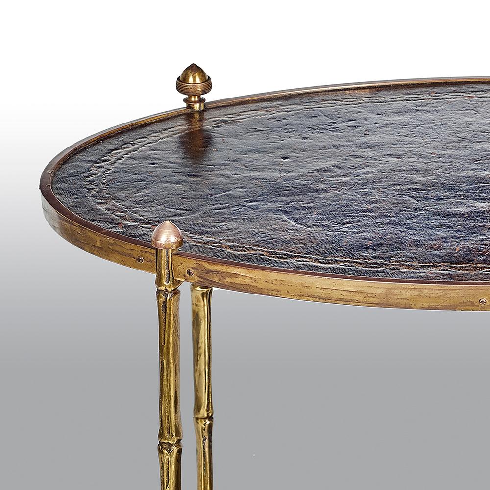 A pair of low brass two-tier étagères with cone finials each oval tier with a leather insert.