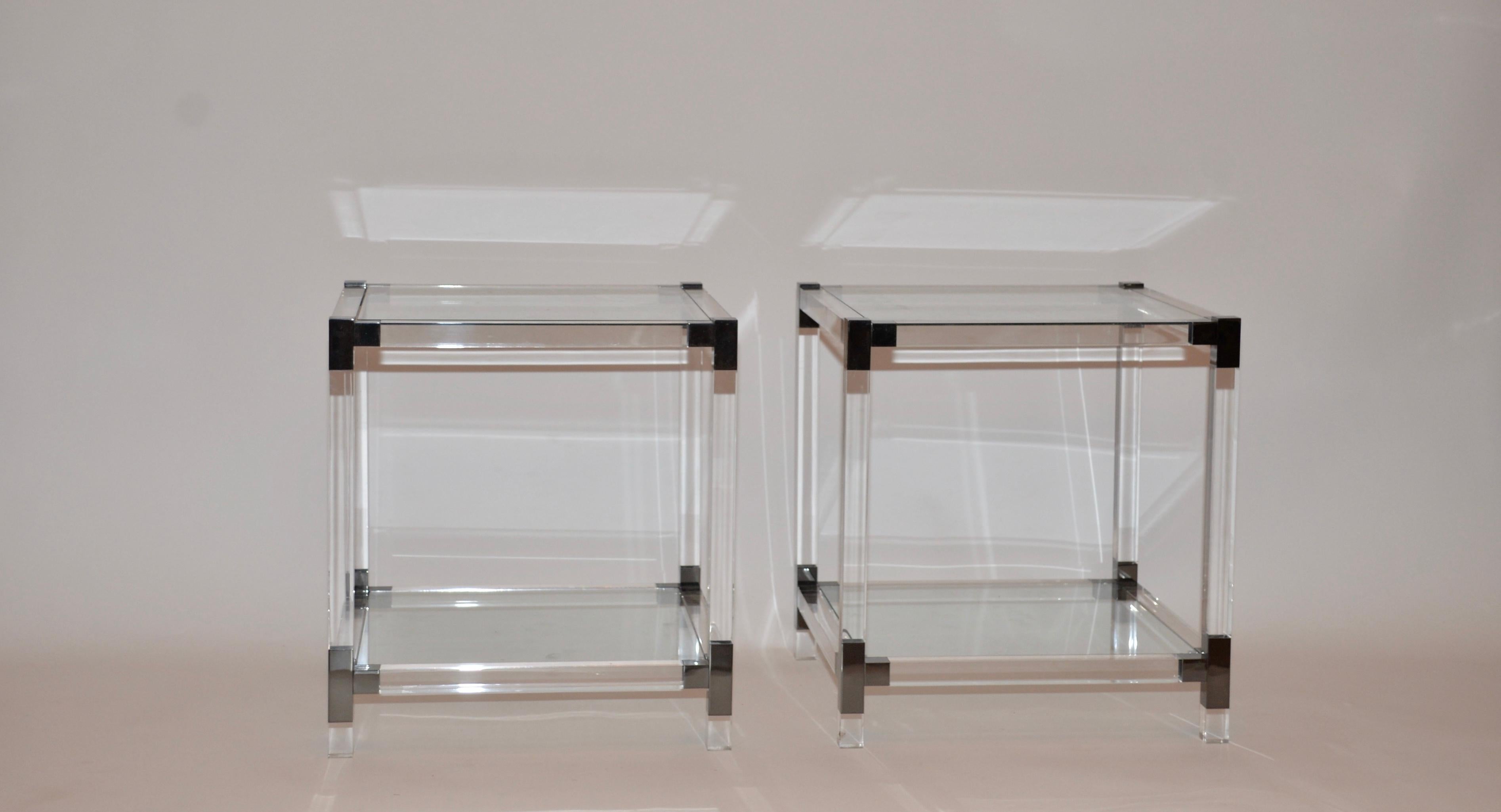 A pair of Lucite and glass Hollywood Regency side tables. The frames are Lucite, two glass shelves with the top shelf being beveled glass. Each corner is finished in chrome.