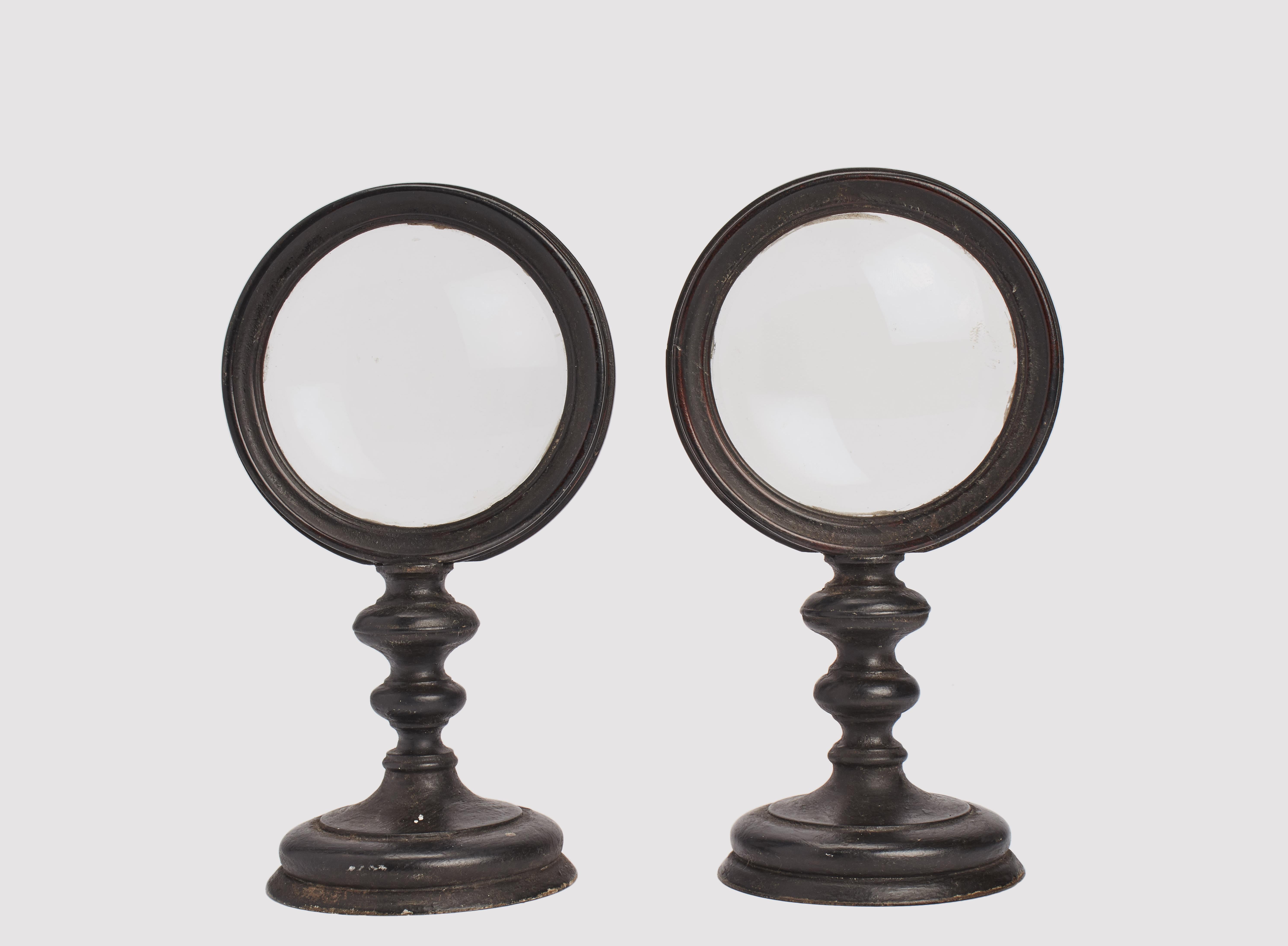 A pair of Wunderkammer  round shape magnifying glasses for scientific purpose with black wooden frames, mounted over a black wooden bases. Italy, circa 1870. 
