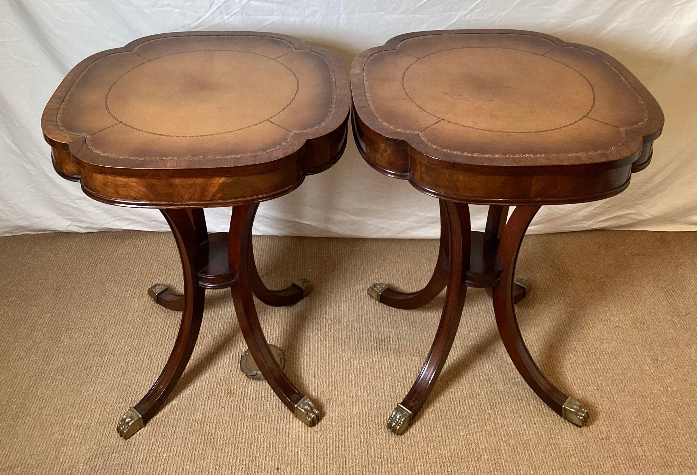 A Pair of Clover shape top mahogany end tables. The tops with tooled leather with thick apron with four graceful sabre legs with brass capped toes.