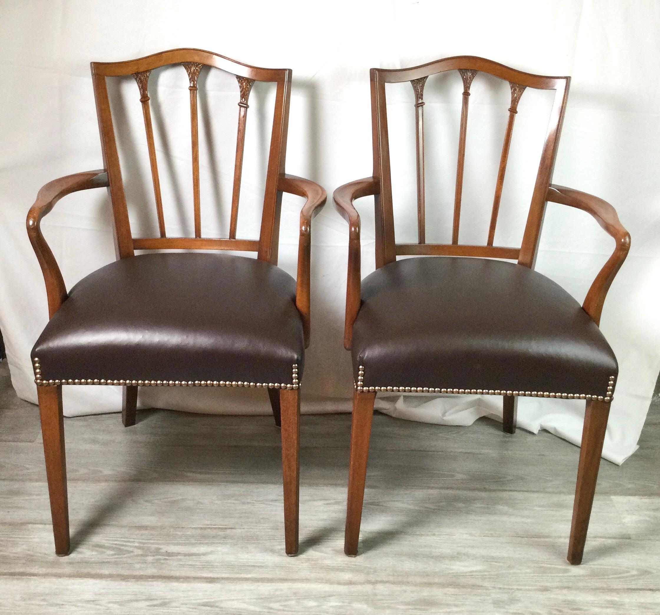 A Classic pair of mahogany and leather Hepplewhite open armchairs. The new dark brown leather seats with brass nail heat trim. Prefect addition in a library or home office.