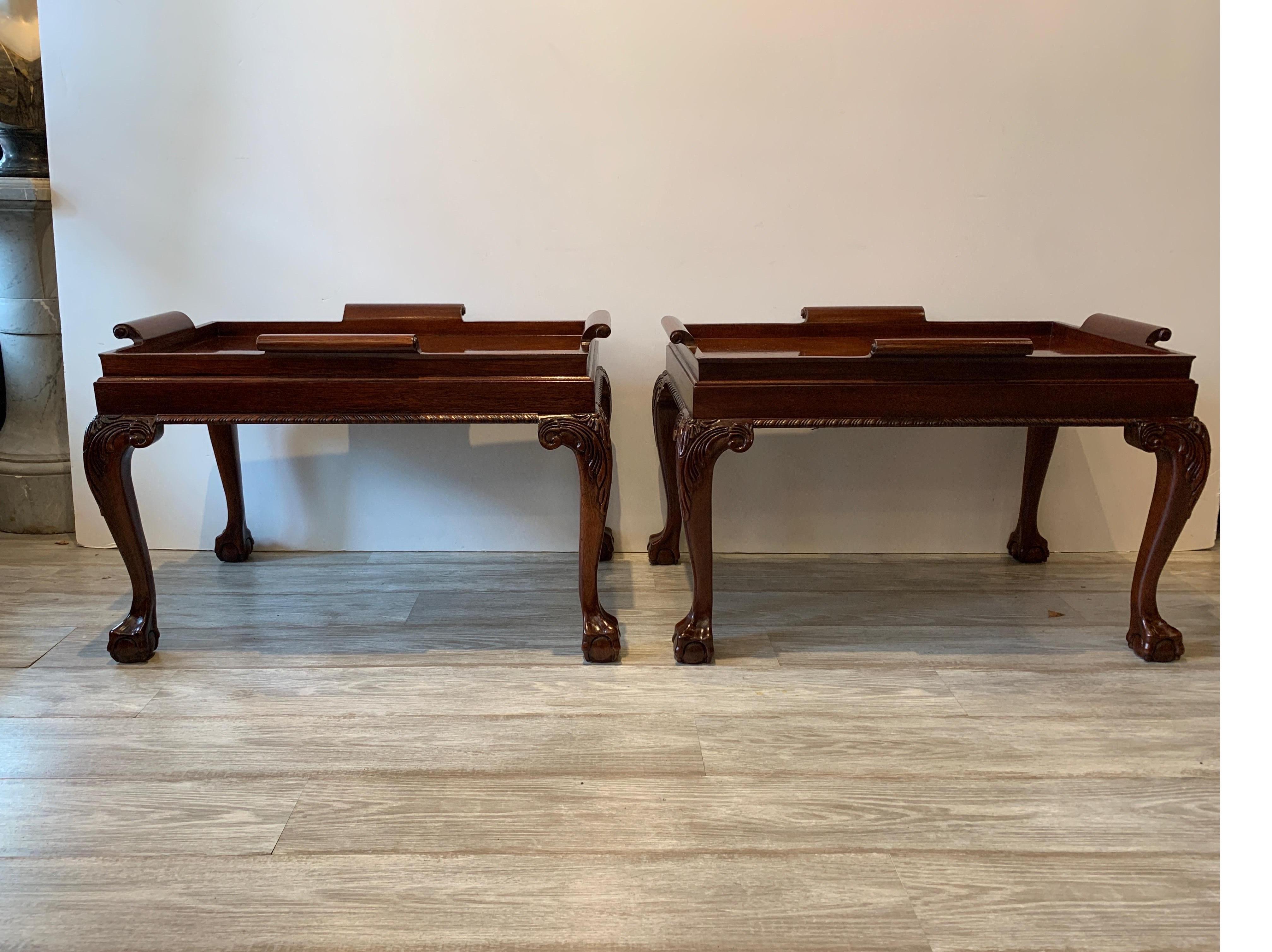 A pair of hand carved mahogany rectangular coffee tables. The Chippendale ball and claw legs with carved knees with tops with a wood gallery edge. The tops are attached but appear as tray tops.