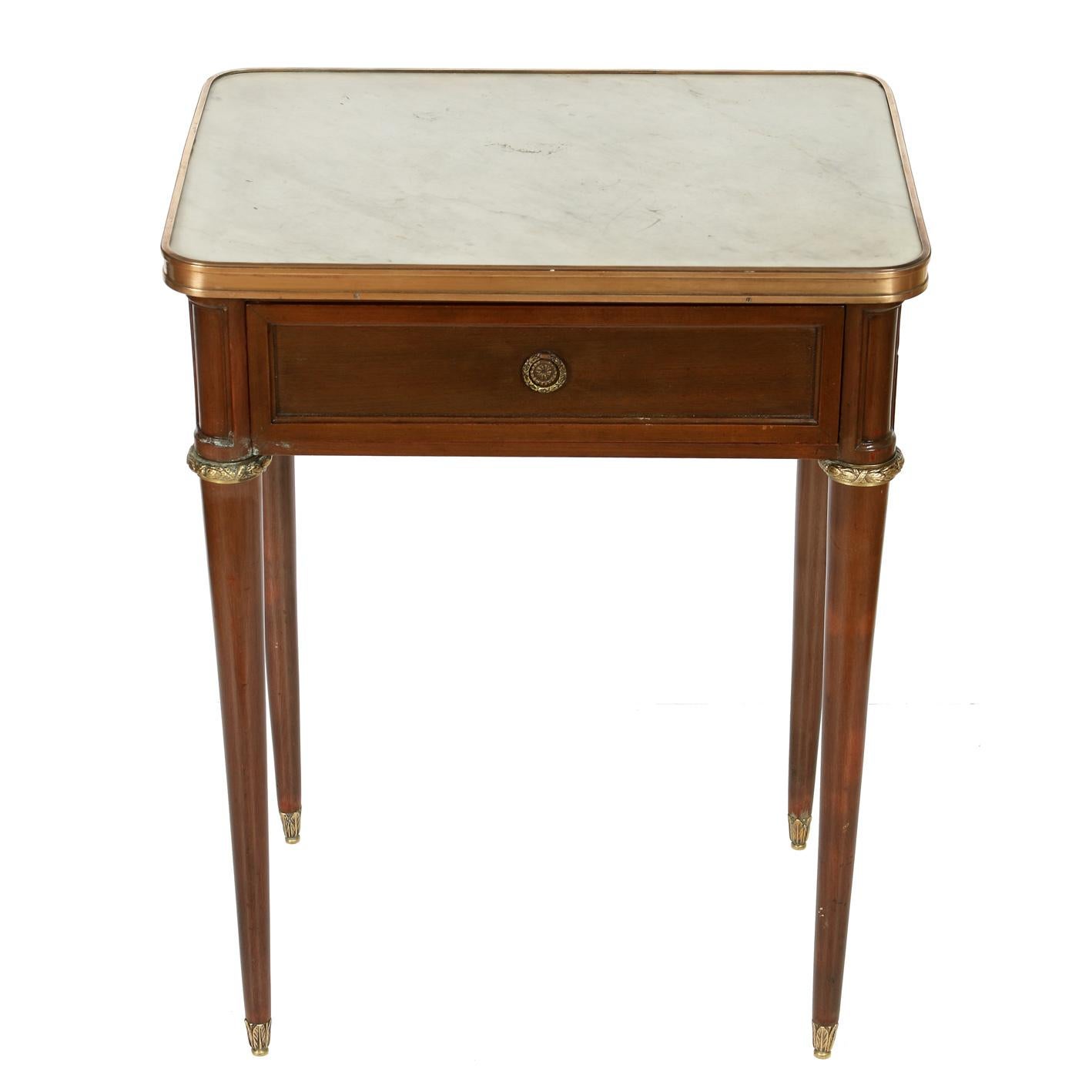 A pair of mahogany nightstands with marble tops, single drawer, brass fittings and round tapered legs.