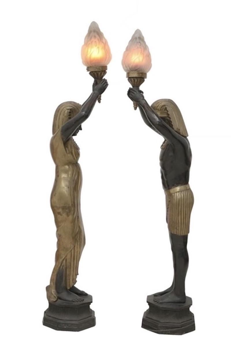 A rare pair of figural torchères, attributed to Maison Jansen, each modelled as ancient Egyptian figures holding a torch lamp 'flame' holder, made from bronze and gilded metal.

Would make a great statement piece for the home, or even a club or