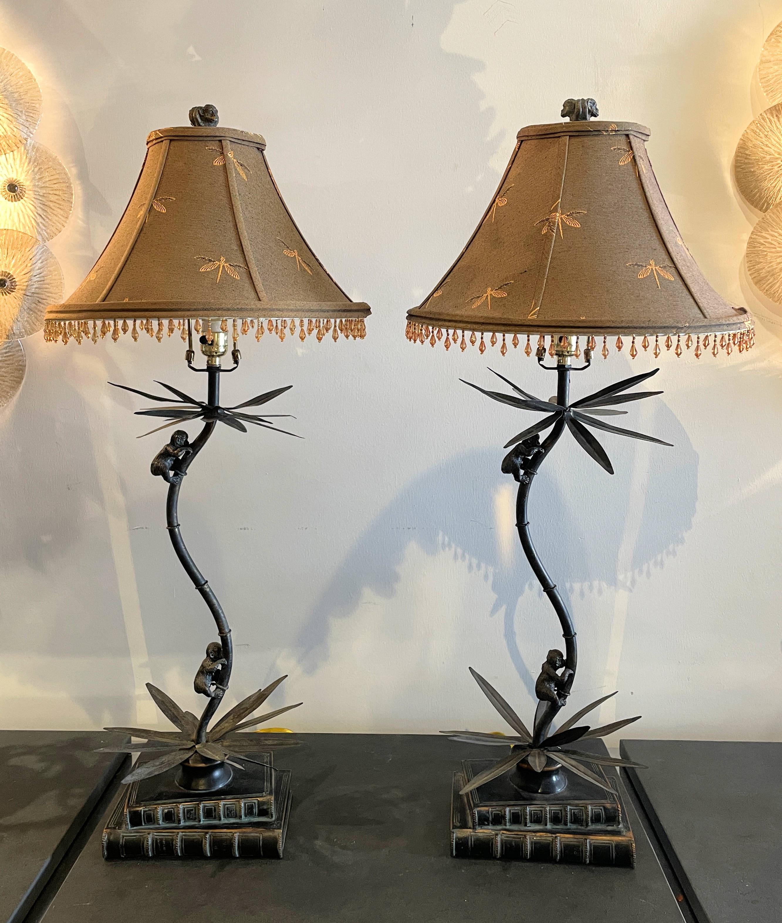 A tropical themed lamp by Maitland Smith. Handmade in America and in the Philippines. The version of the climbing monkeys on a palm tree with the stacked book base is rare. The custom lamp shades with woven dragon flies are adorned with glass beads.