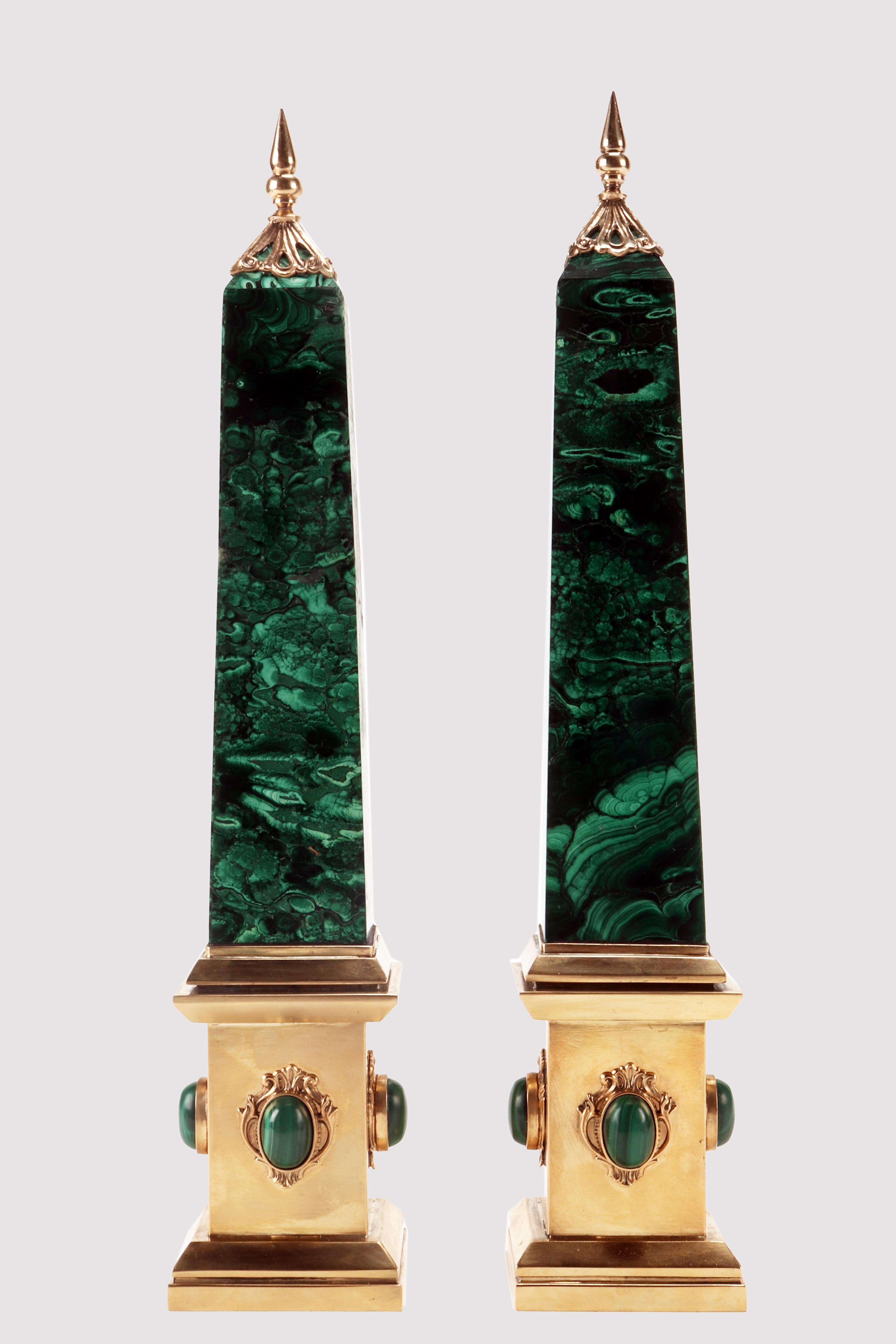 A pair of Grand Tour obelisks. Made of Malachite. The base, the feet and the tips of the obelisks are made of gilded bronze. At the center of the sides of the plinth, there is a bezel with an oval cabochon malachite. Italy second half of the 19th