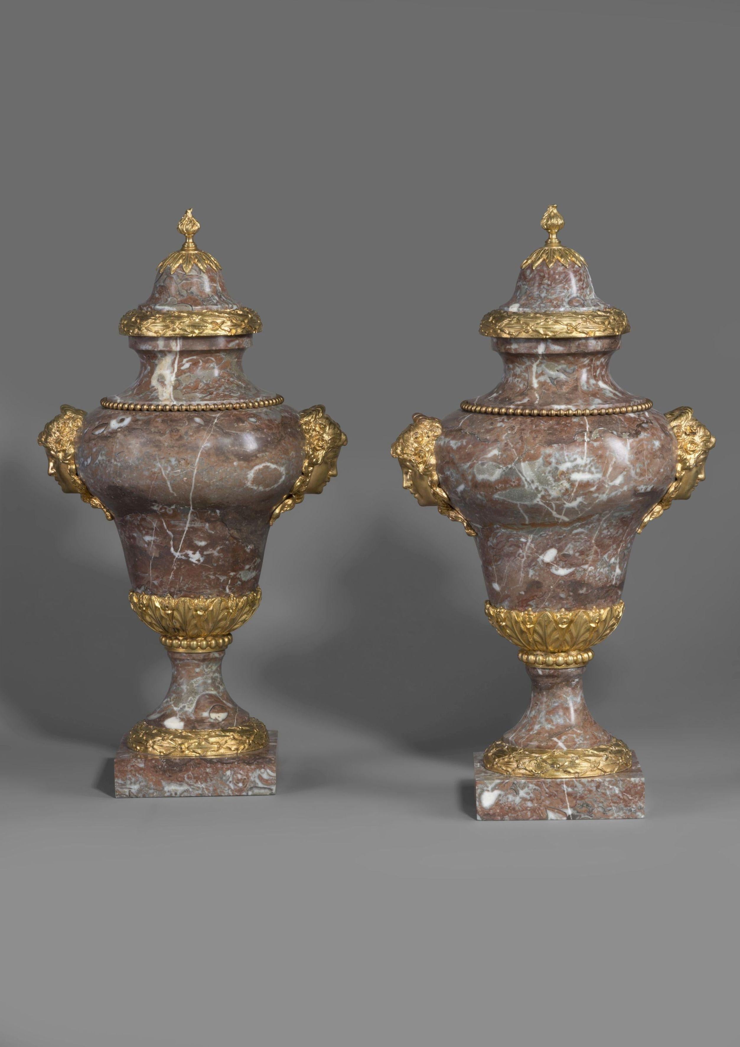 A pair of gilt-bronze mounted Incarnat Turquin marble vases in the manner of Pierre Gouthière.

Each vase is mounted with finely cast gilt bronze female masks and foliate garlands. 

Pierre Gouthière (1732-1813) son of a saddle maker, rose to become