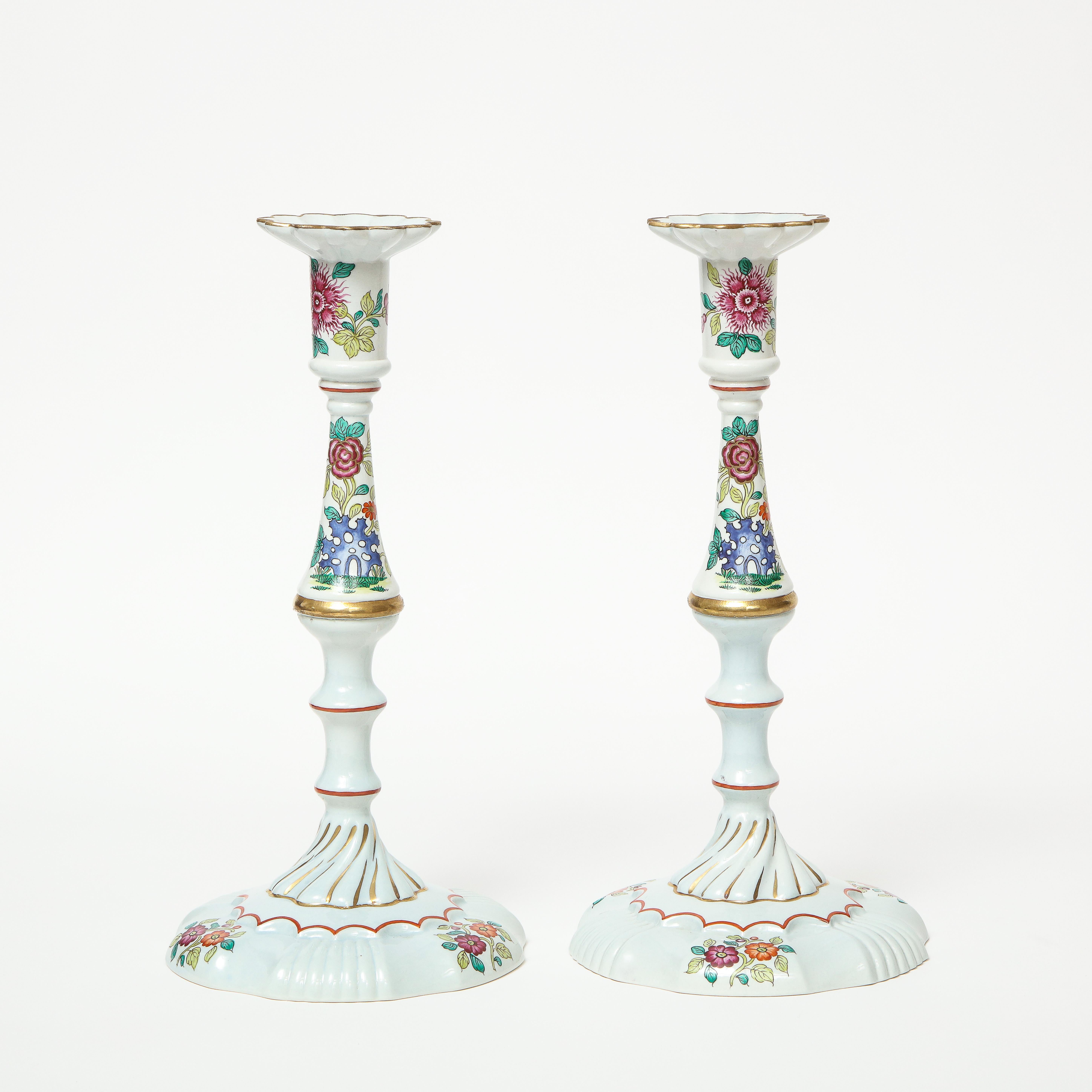 Each of Rococo design; painted overall with polychrome Chinese style floral and rock motifs, each knob gilt-rimmed. Drilled so they can be turned into lamps.