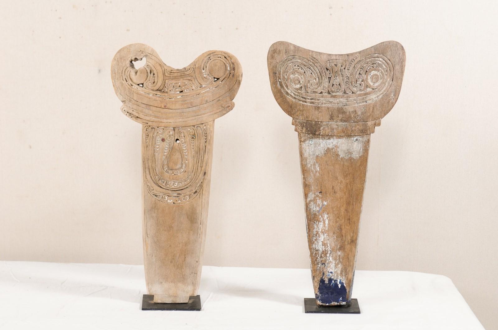 A pair of decoratively carved wood splash boards from the southeastern region of Papua, New Guinea, presented on custom stands. This pair of vintage tribal boards have been carved from a single piece of wood, and were typically used in the front of