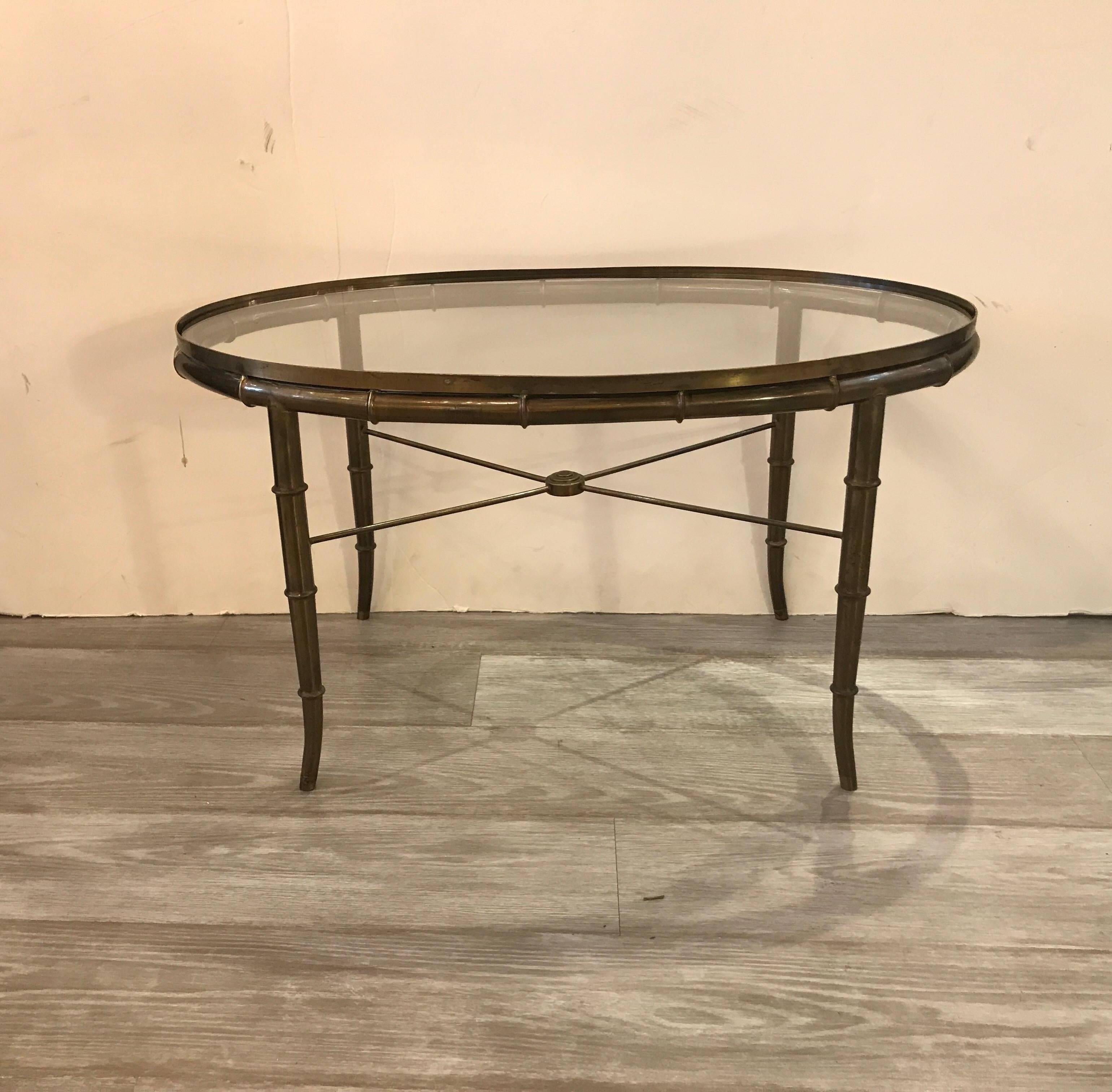 A diminutive pair of Mastercraft patinated brass and glass oval coffee tables. The gently splayed bamboo motif legs with X-stretcher bases. Priced for that pair but if you are interested in one.